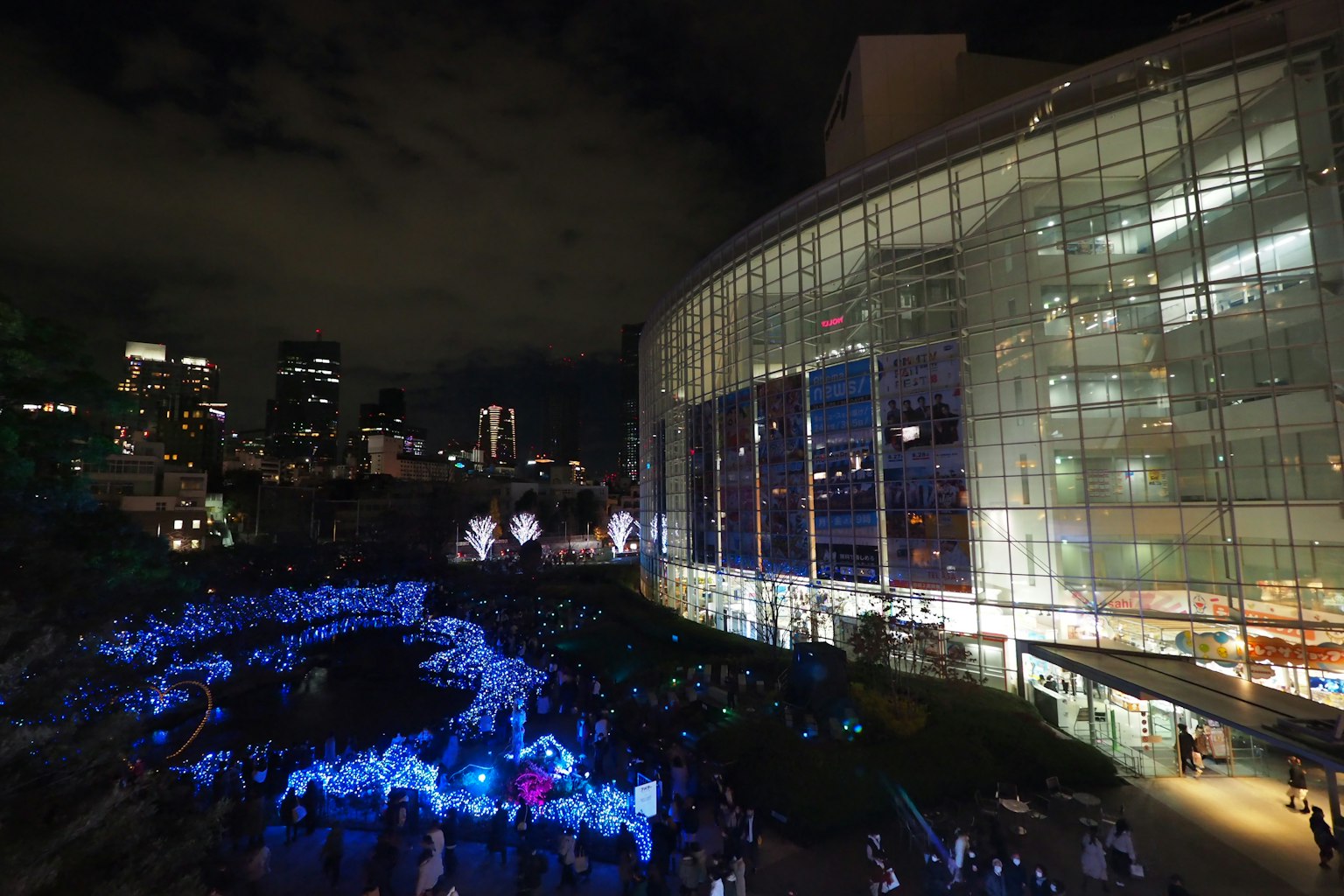 Urban night scene featuring glowing blue lights and a modern building
