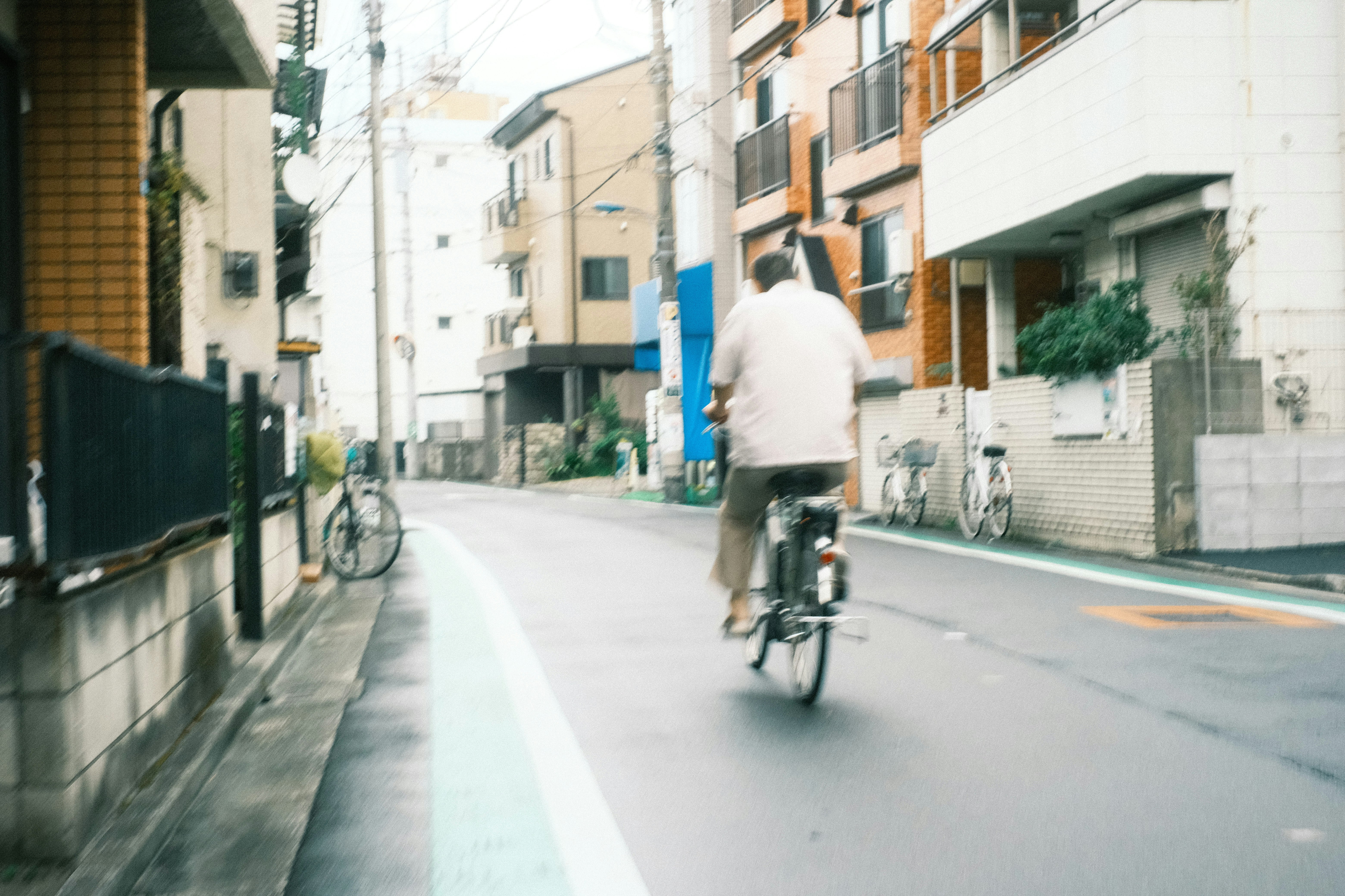 A man riding a bicycle through a narrow street in an urban setting