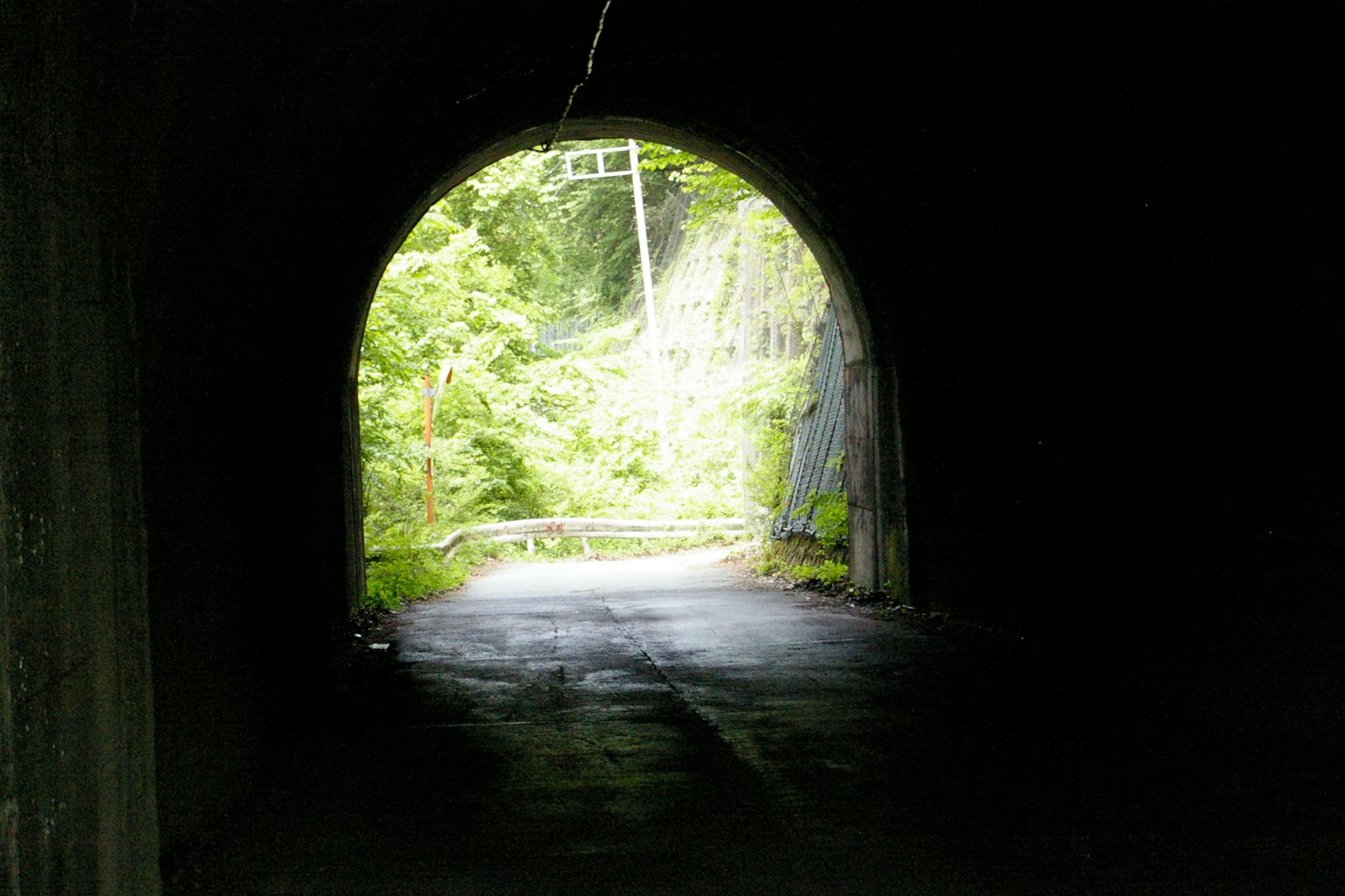 Un tunnel scuro che porta a un paesaggio verde luminoso