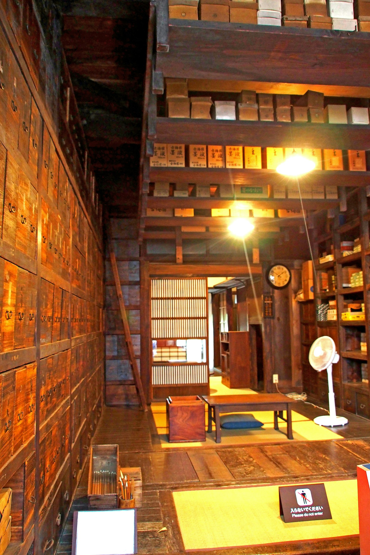 Interno di una stanza tradizionale con pareti in legno e scaffali illuminazione e orologio un tavolo e un ventilatore