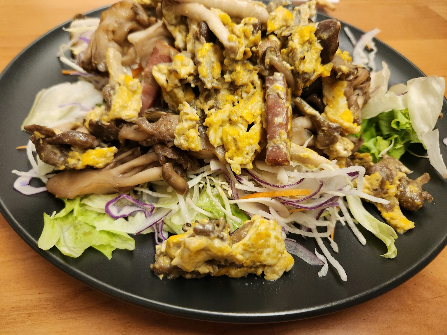 黑色盘子里的炒蛋和肉的菜肴