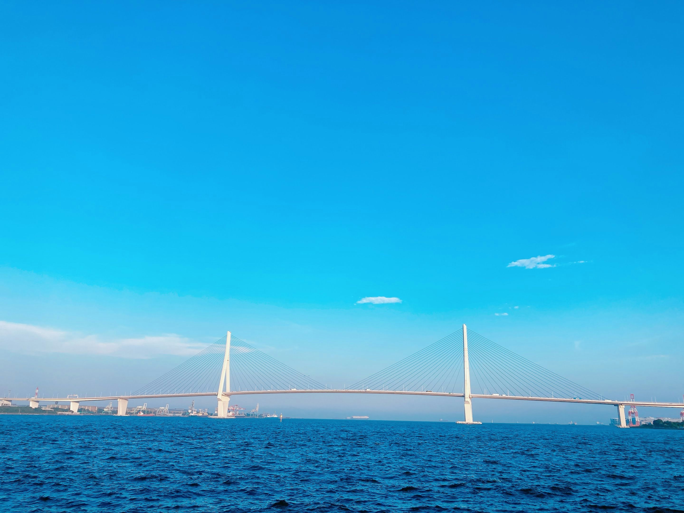 青空の下の海と2本の橋脚が見える海上の風景
