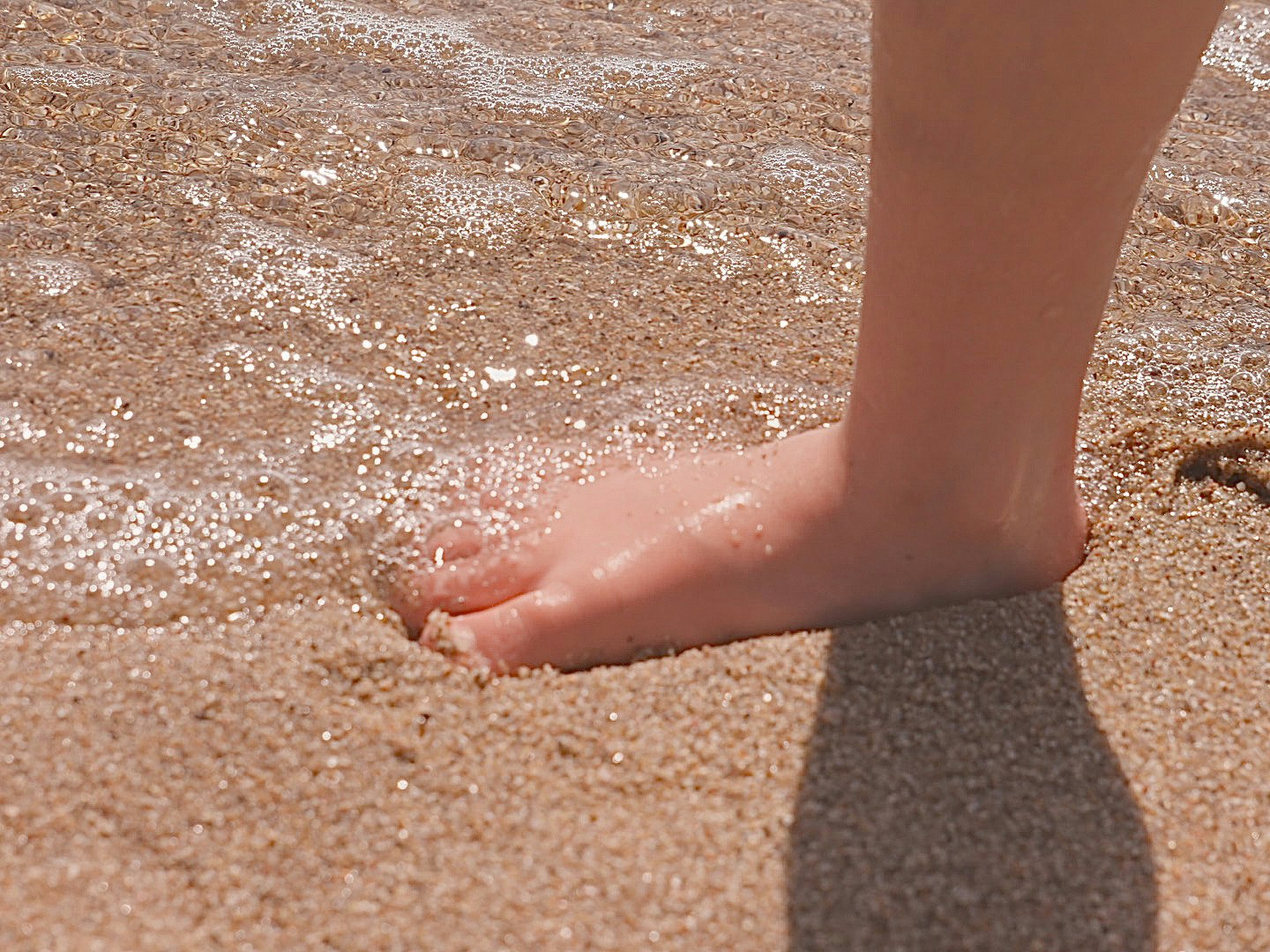 砂浜で足を洗う手と足元の水しぶき