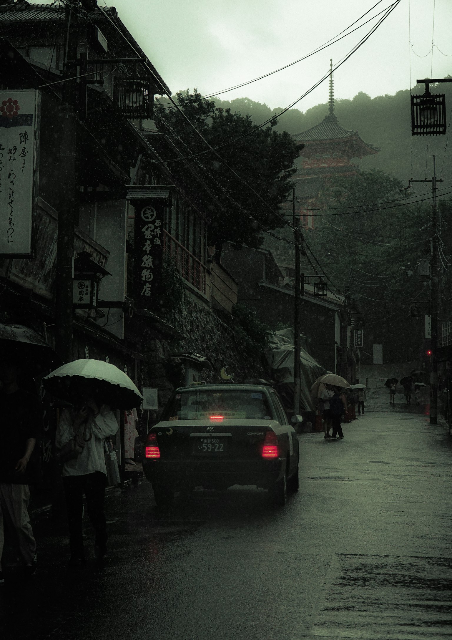 안개 낀 분위기에서 비를 맞고 있는 자동차와 보행자가 있는 거리 풍경