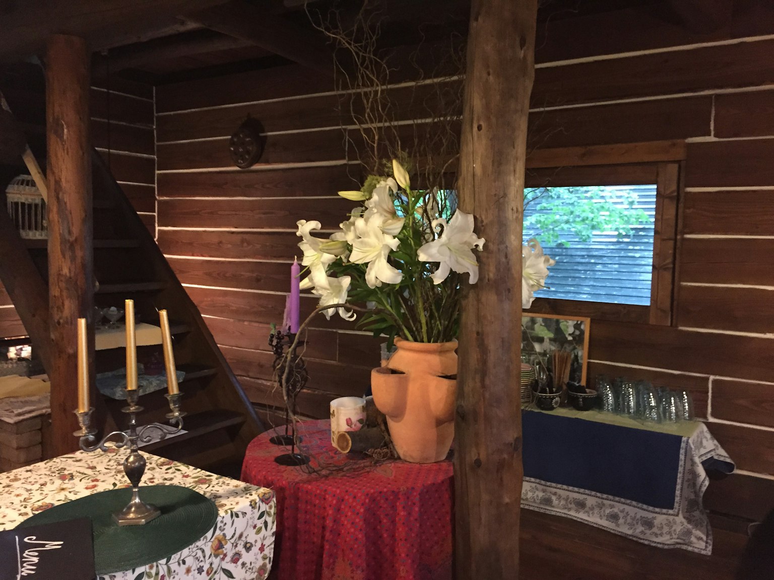 Gemütliches Interieur mit Holzwänden und Tischen mit weißen Blumen in einem großen Topf