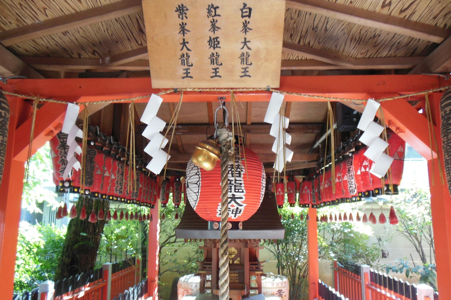 Interior de un santuario con un torii rojo y un altar con campana