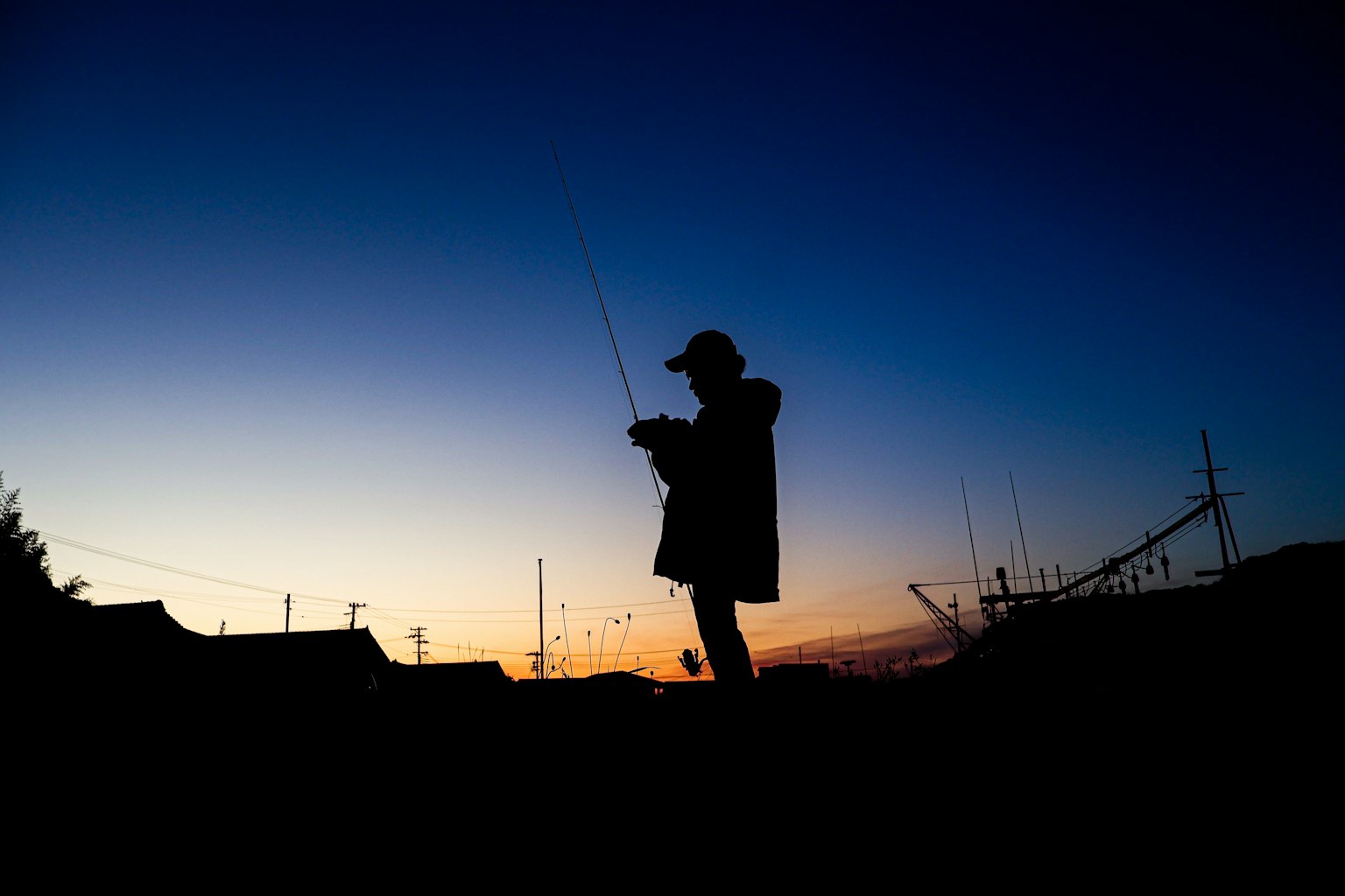 Silhouette di una persona che pesca al tramonto