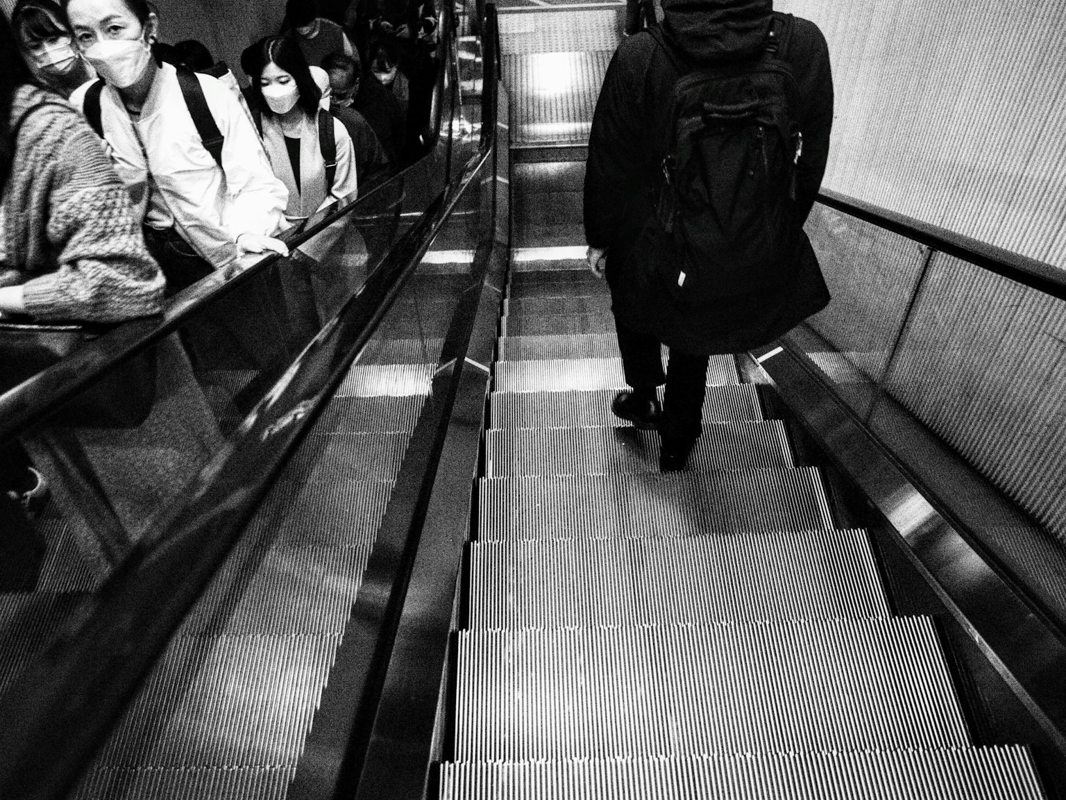 Des gens alignés sur un escalator noir et blanc