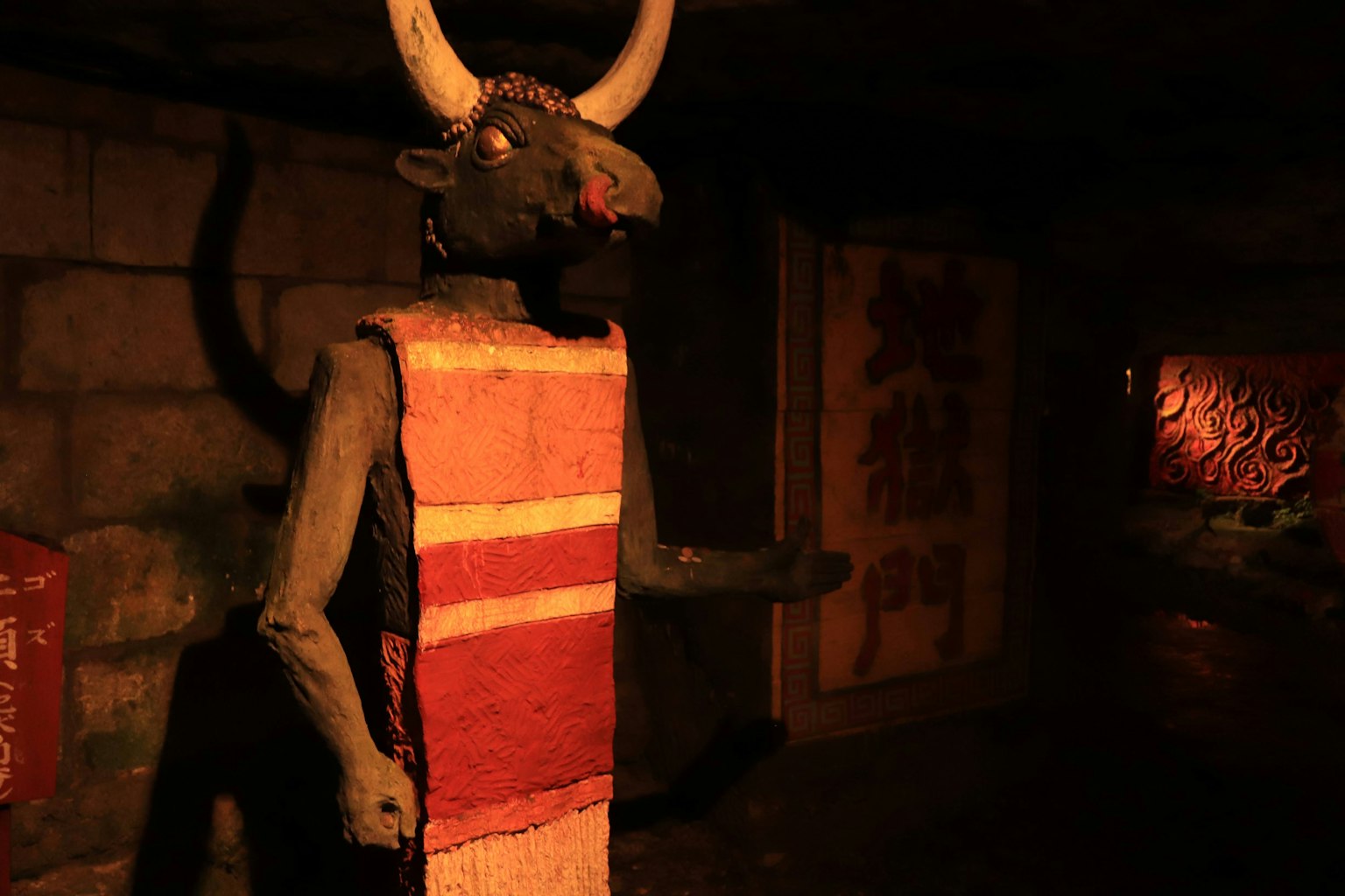 Una impresionante estatua de toro se erige en un espacio oscuro con muros antiguos al fondo