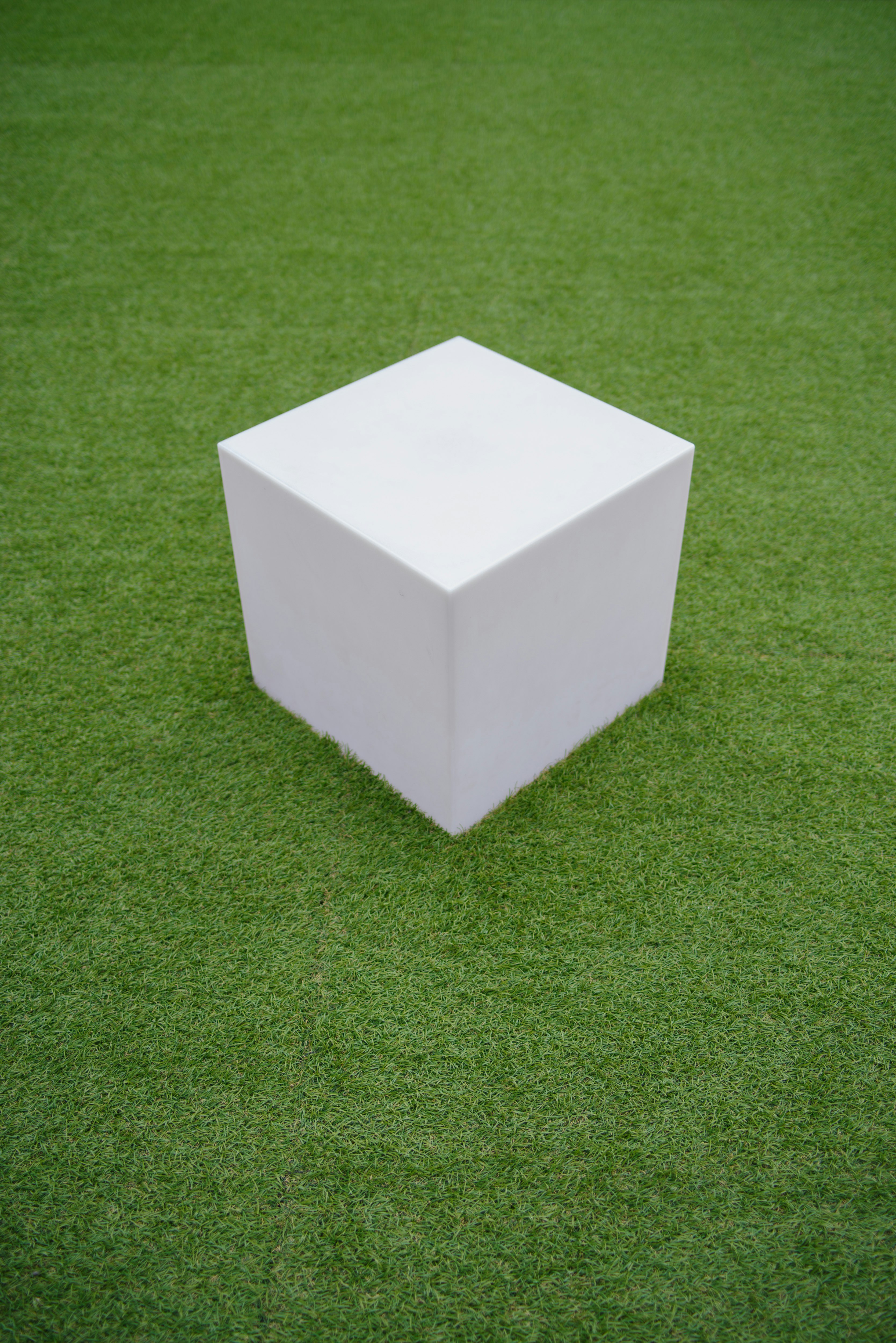 cube blanc posé sur de l’herbe verte
