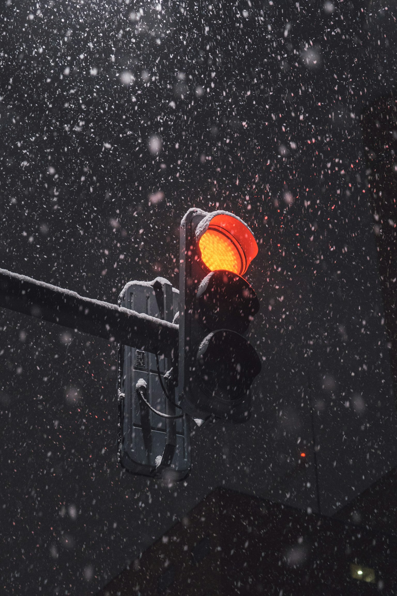 Gros plan d'un feu de circulation rouge illuminé dans la neige tombante la nuit