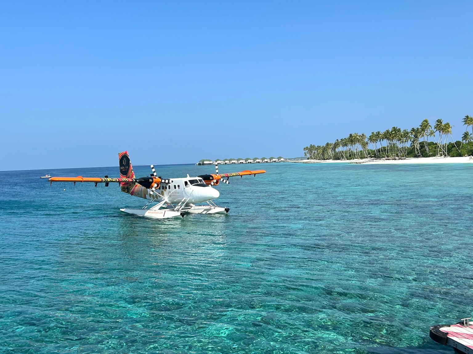 Hydravion sur une eau claire avec une plage tropicale en arrière-plan