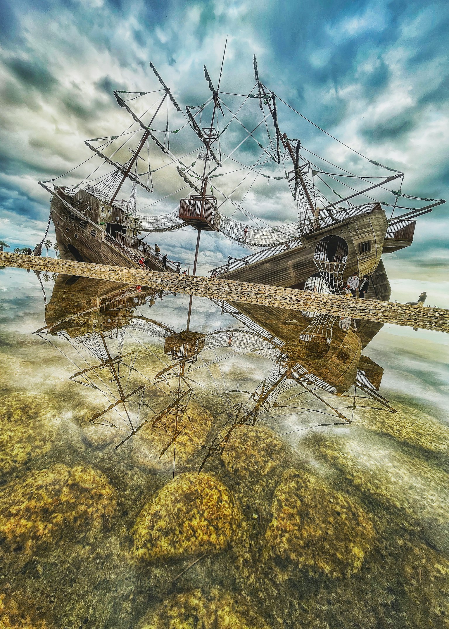 Barcos antiguos reflejados en el agua con un cielo nublado
