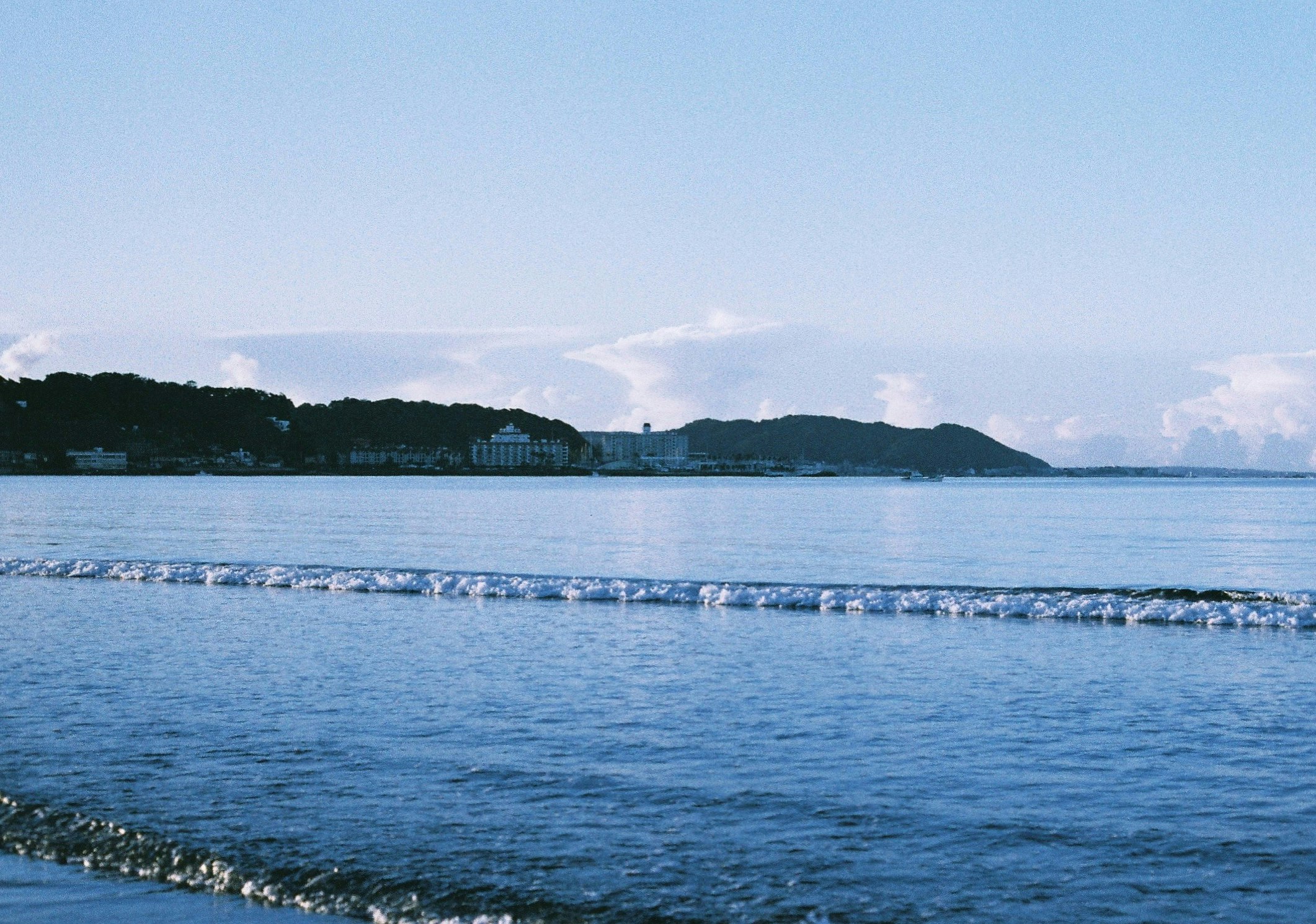 波打ち際に並ぶ小さな石と遠景の海岸線