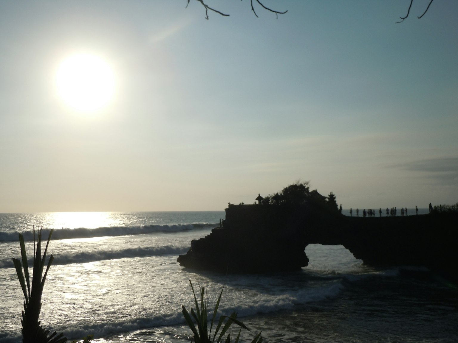 Pemandangan pantai yang indah dengan matahari terbenam dan lengkungan batu di latar belakang