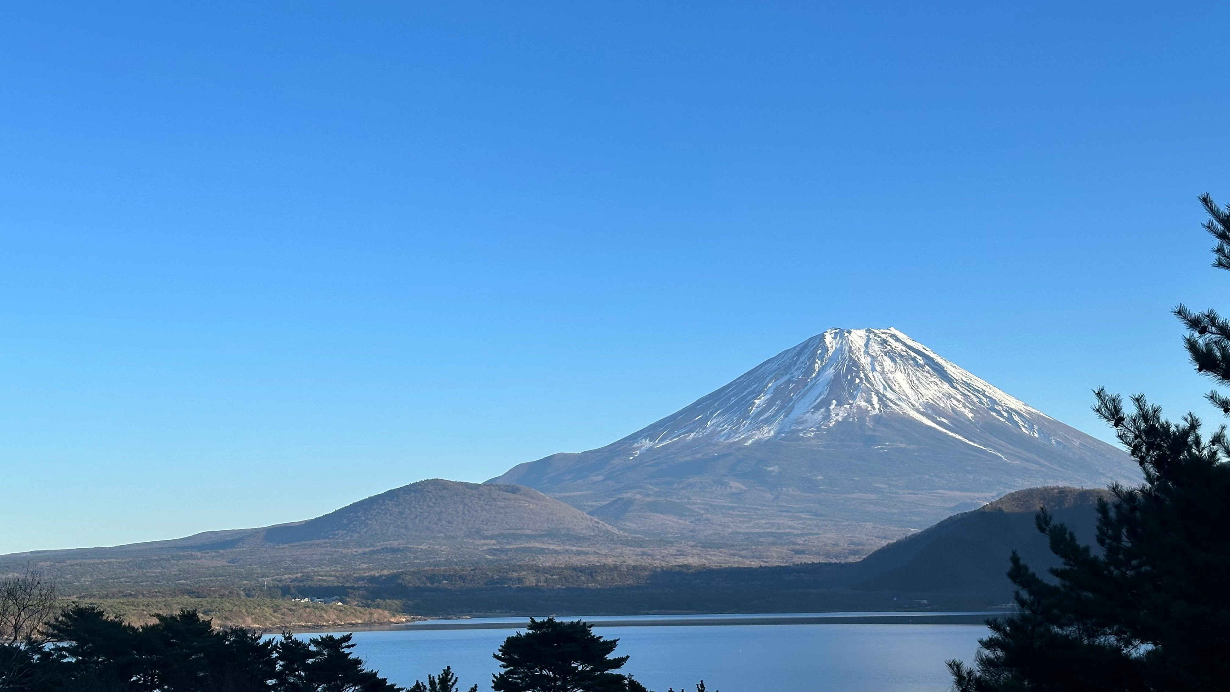 Lake shoreline view with Mount Fuji under a clear blue sky