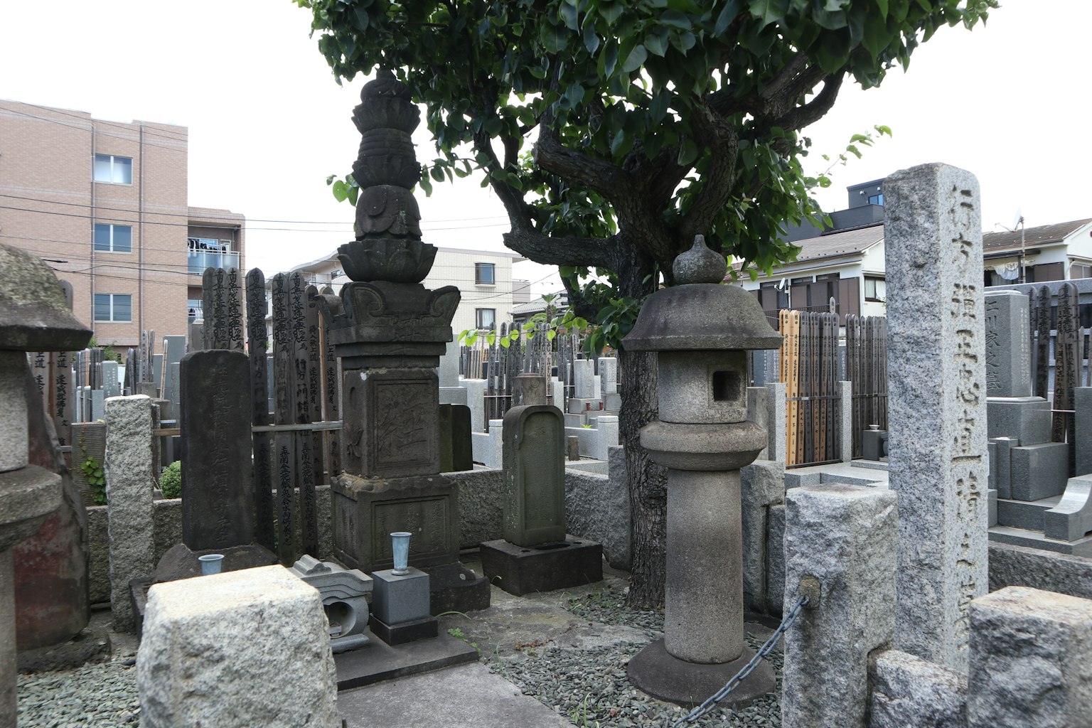 Scène de cimetière avec des tombes en pierre des lanternes et un arbre