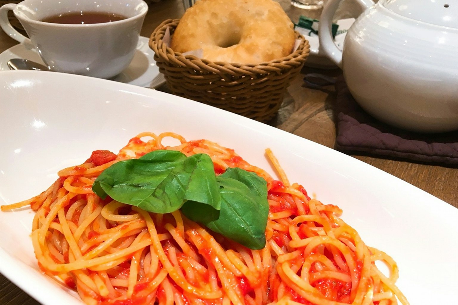 Piring spaghetti dengan saus tomat dihias dengan daun basil segar
