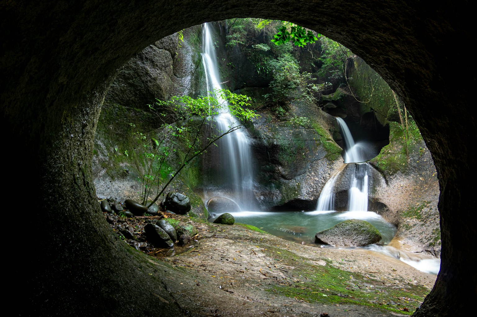 View of a beautiful waterfall and lush nature through a tunnel