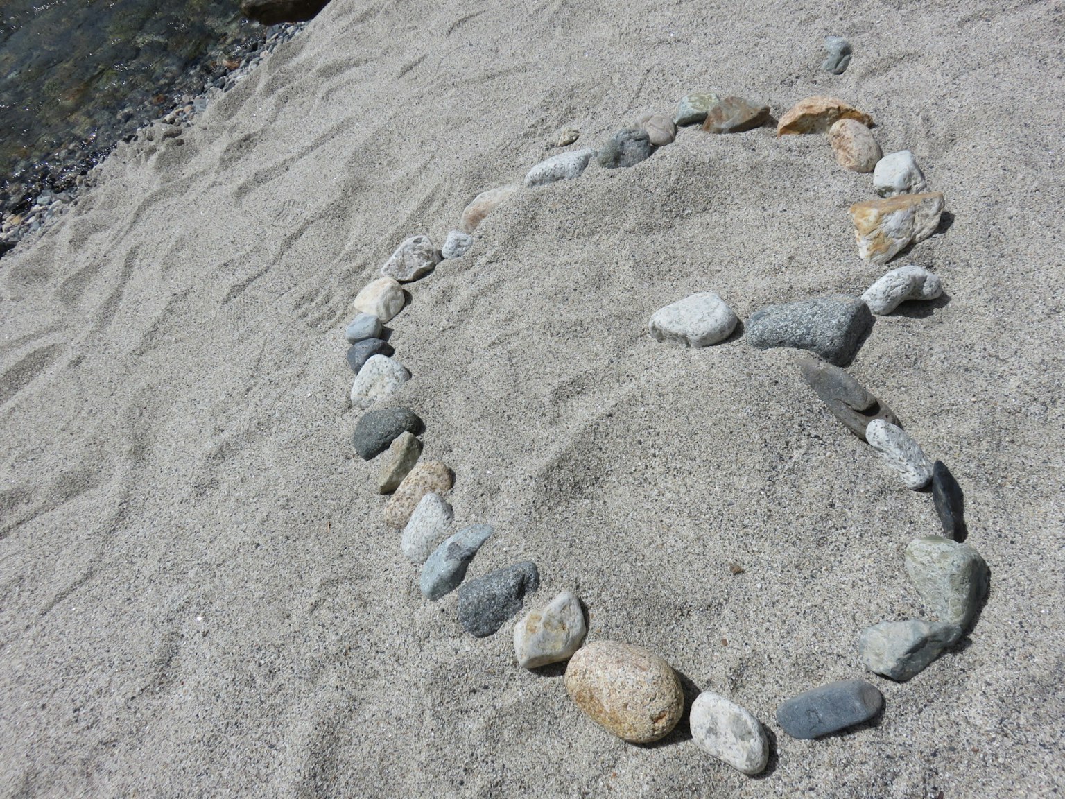 Numero 6 creato con sassi sulla spiaggia di sabbia
