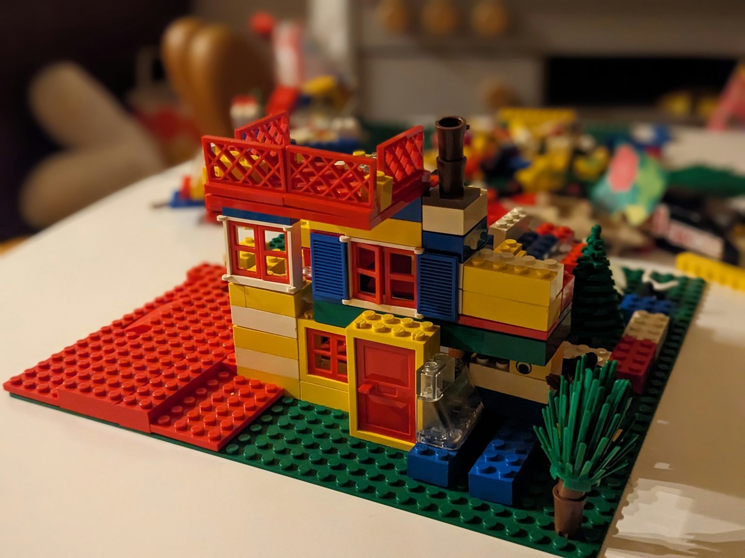 Rumah Lego berwarna-warni diletakkan di atas dasar hijau dengan atap merah