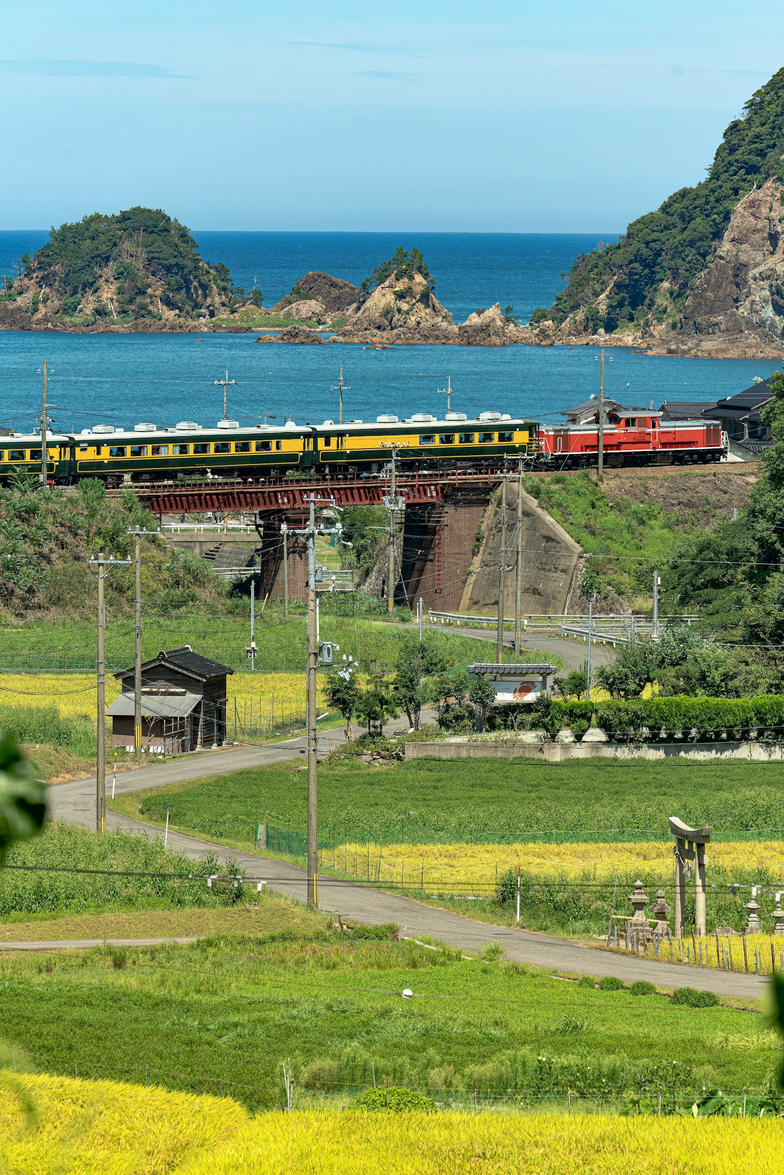รถไฟหลากสีที่วิ่งผ่านภูมิทัศน์ที่สวยงามมีทะเลสีน้ำเงินและภูเขา