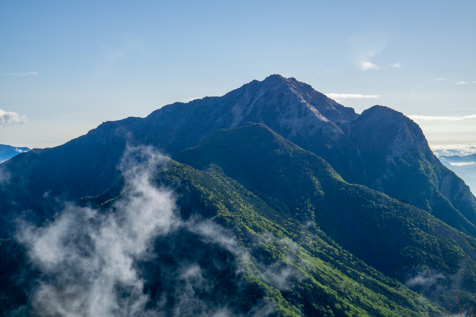 Paysage de montagne majestueux entouré de collines verdoyantes et de nuages