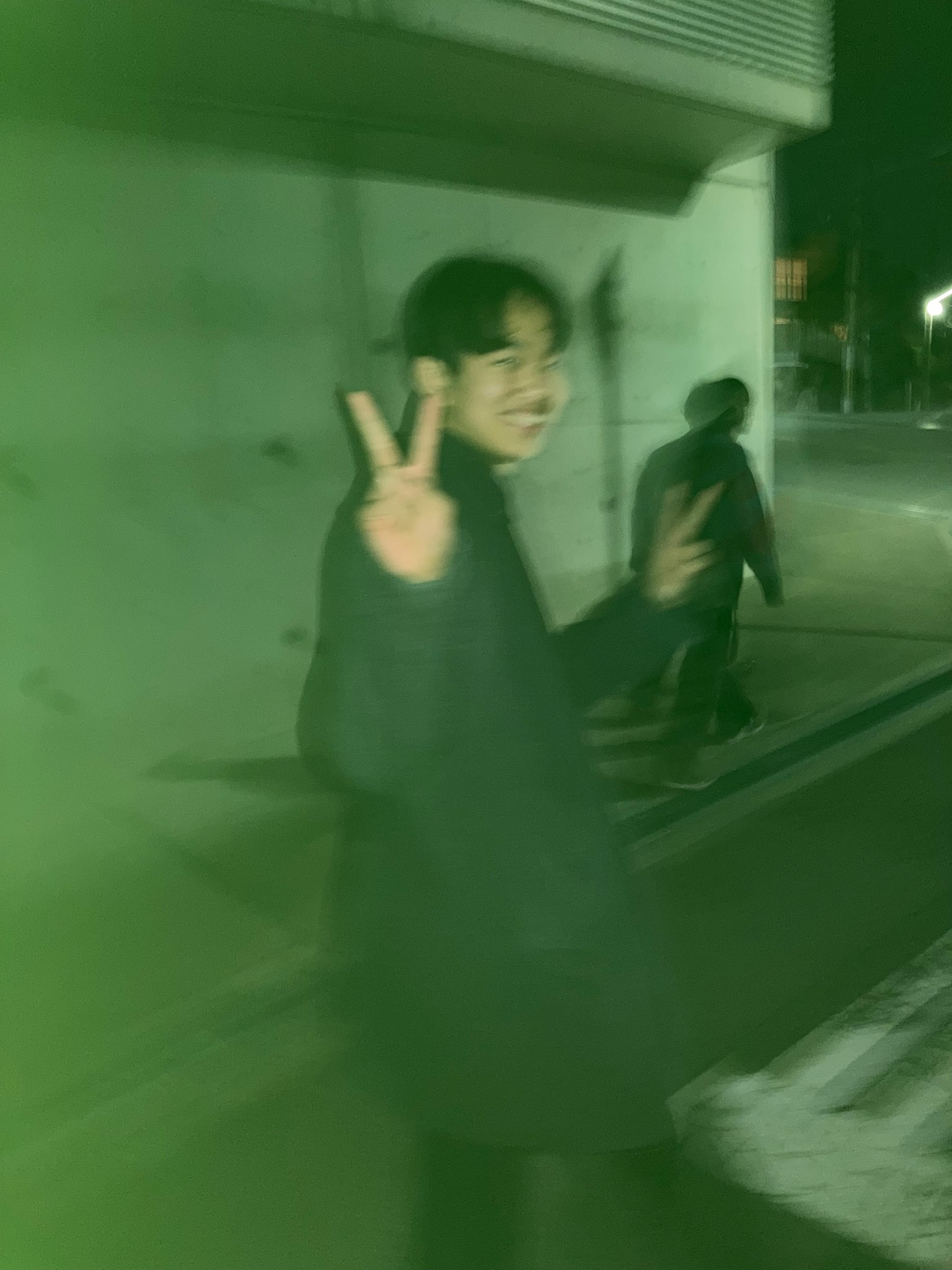 一个年轻男子在绿色背景下做出和平手势