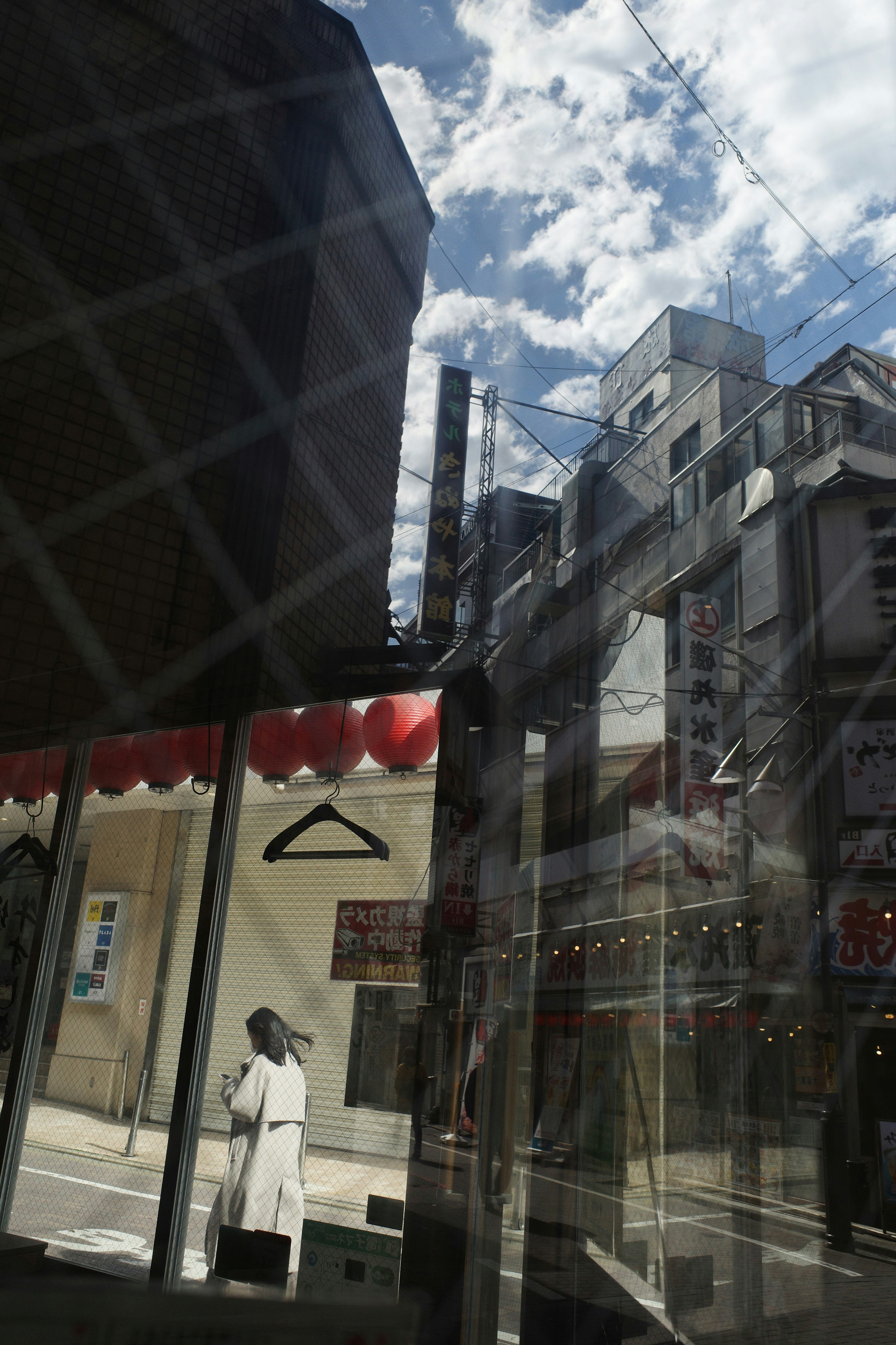 空とハンガーのすきまが見える路地の商店街の軒先