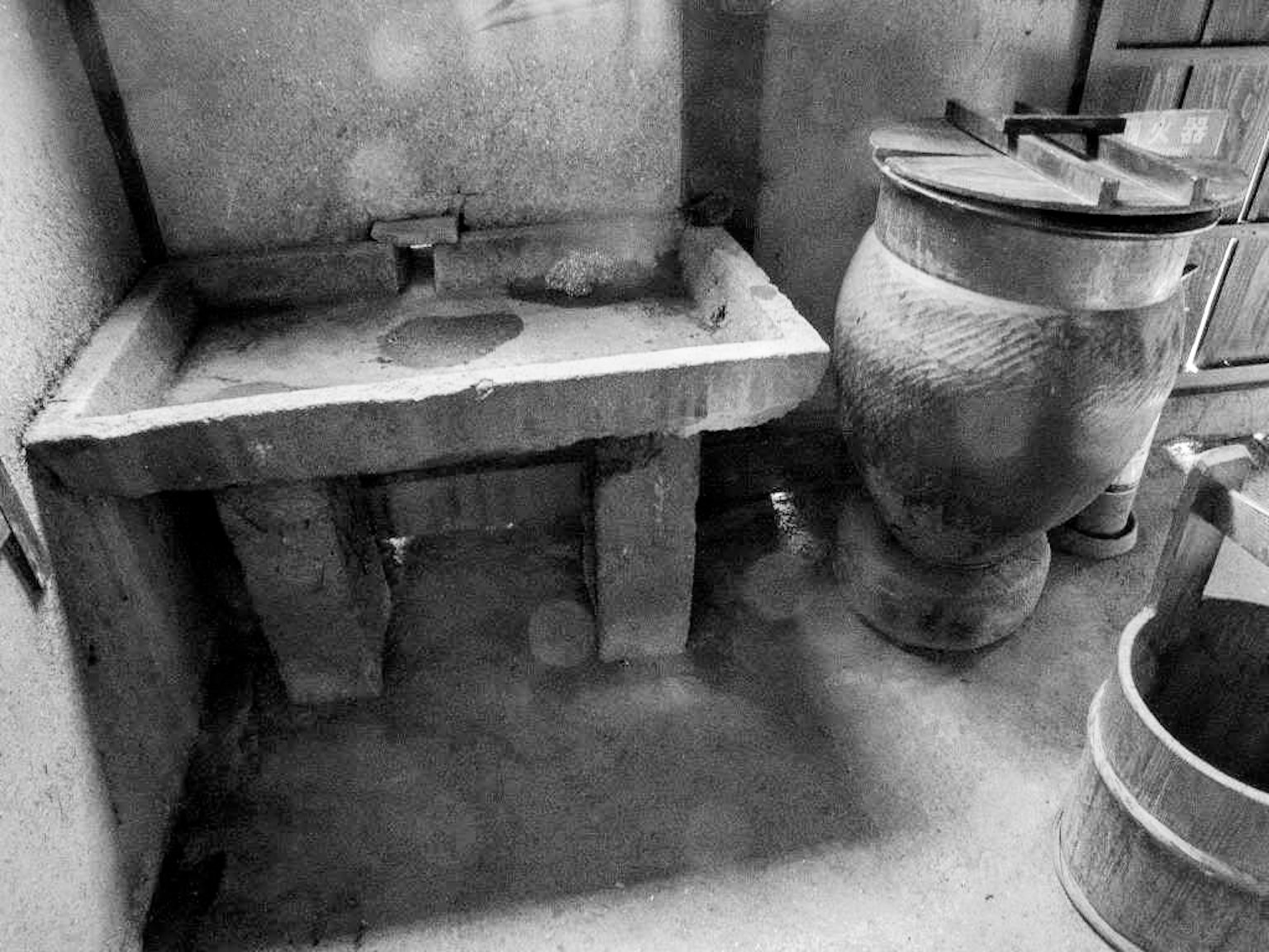 Interno di una stanza con un vecchio lavandino in pietra e un vaso in ceramica