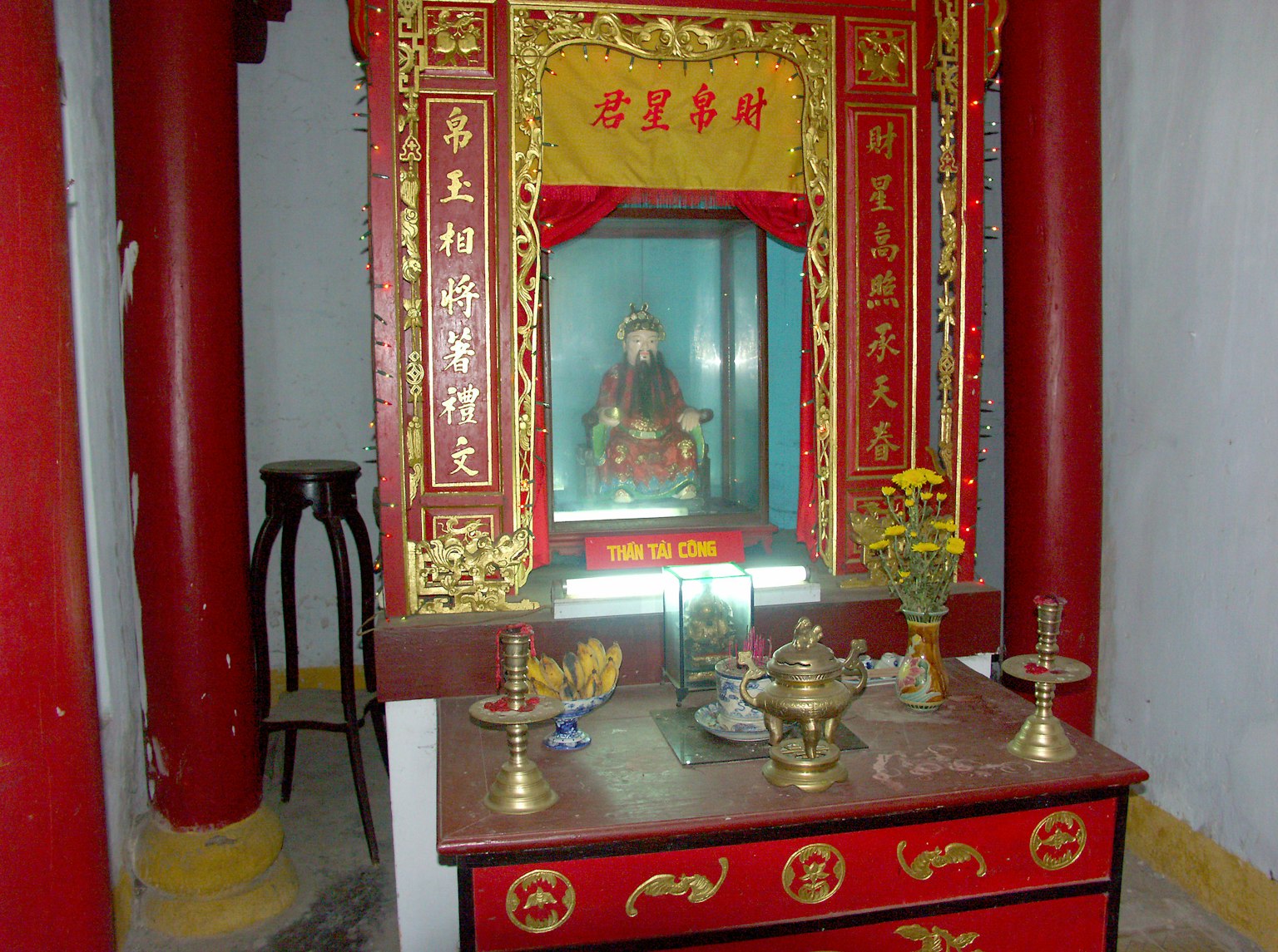 Interior view of an altar with a Buddha statue surrounded by red and gold decorations