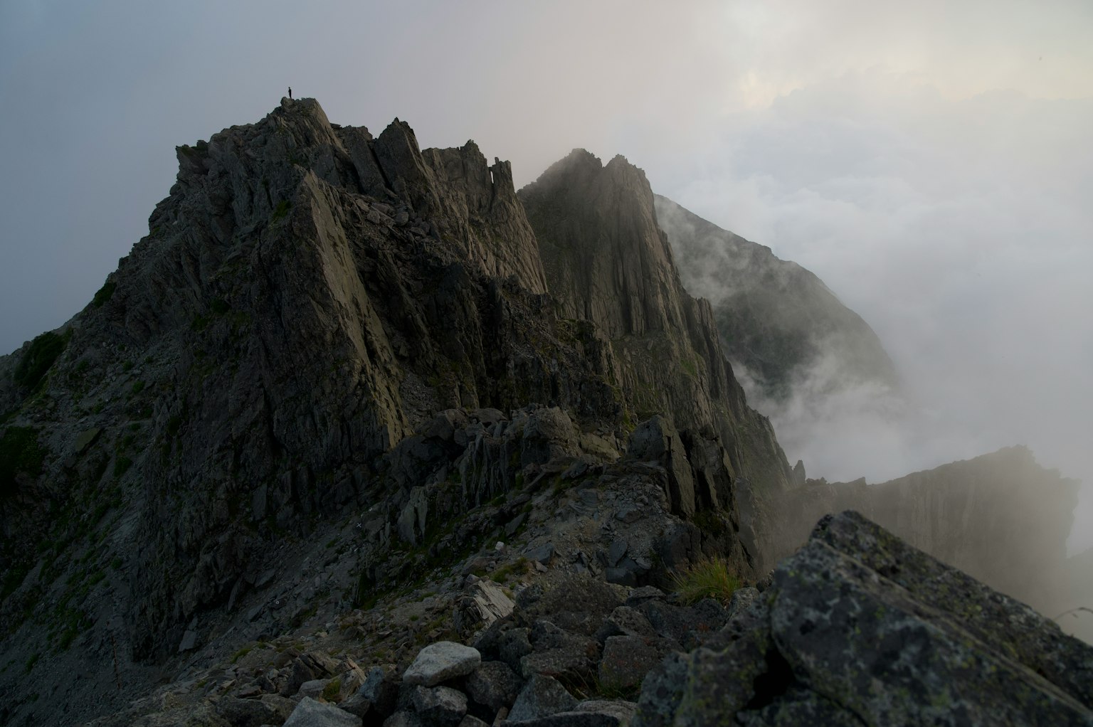 Un paesaggio montano avvolto nella nebbia con formazioni rocciose frastagliate