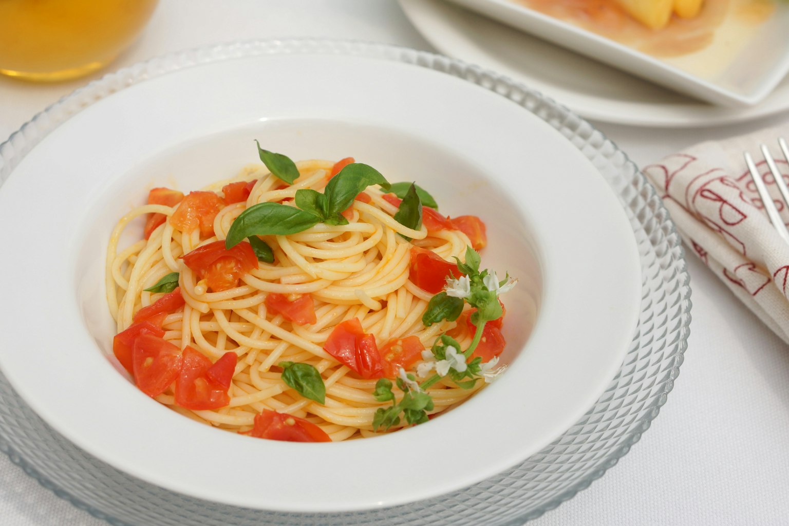 Spaghetti with tomatoes and basil served in a white bowl
