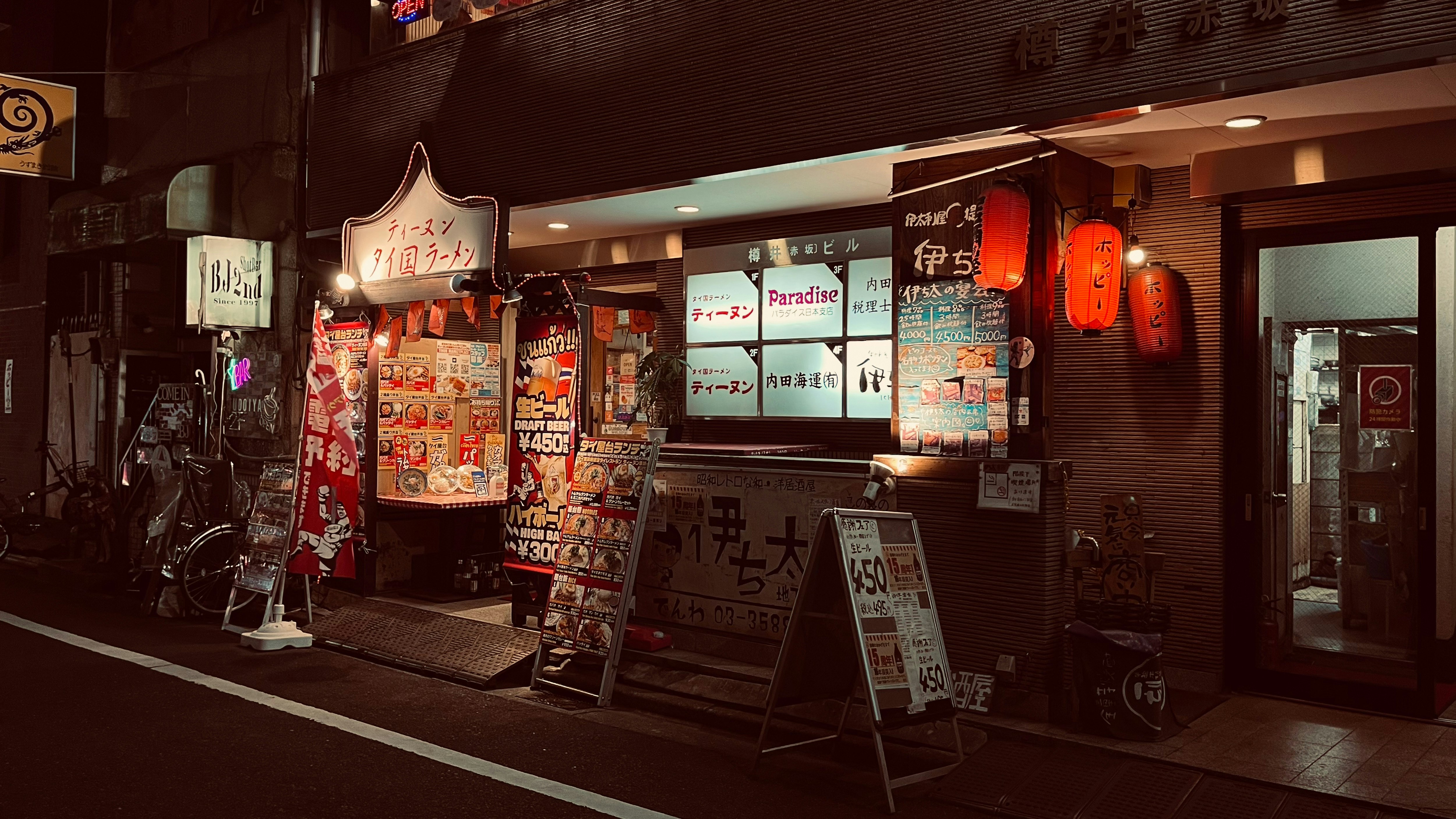 夜のタイ料理店の看板と店先の屋台メニュー