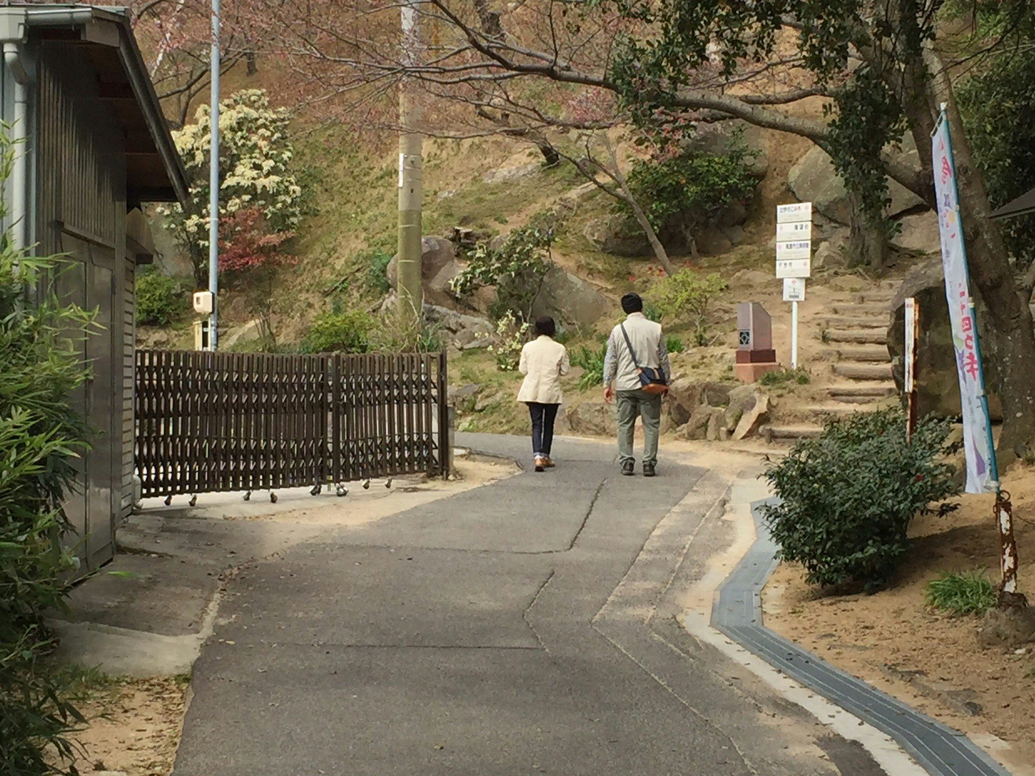 坂道を歩く人々と紅葉の並木が続く小道