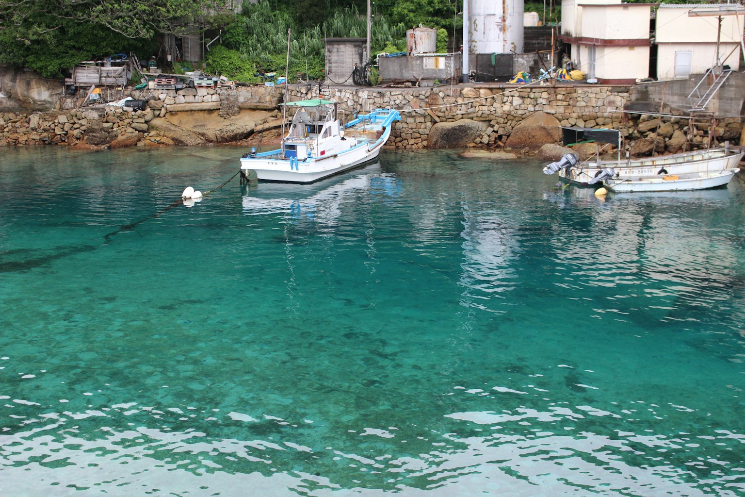 小船漂浮在清澈的水面上，有岩石海岸