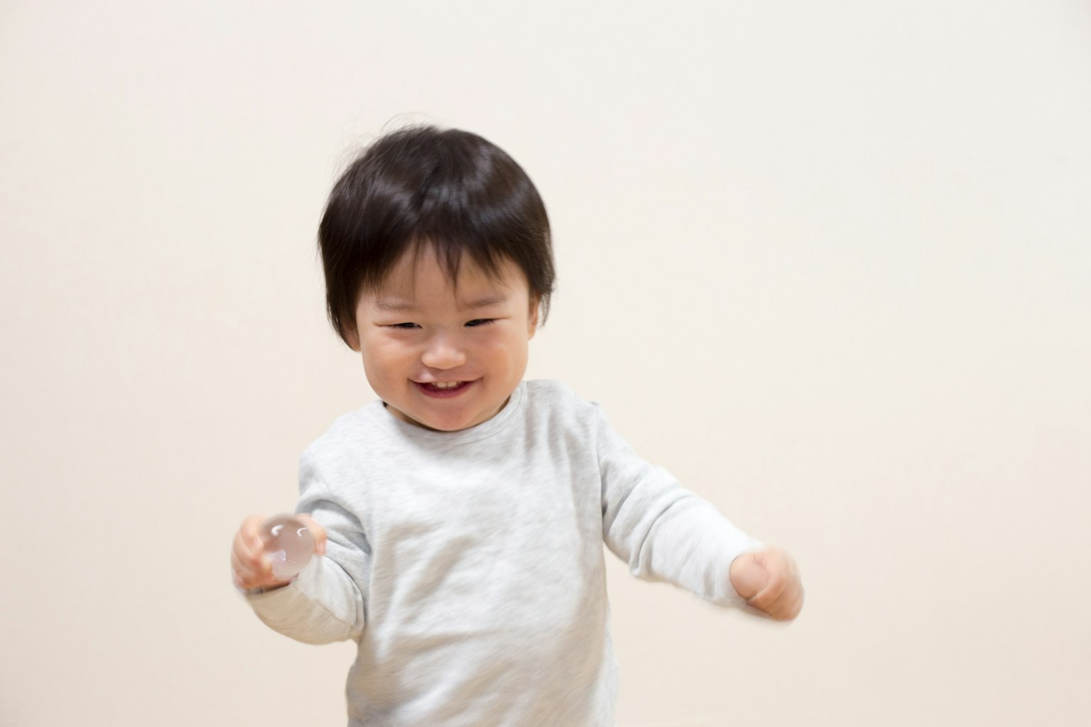 Enfant souriant jouant avec un objet transparent sur fond blanc
