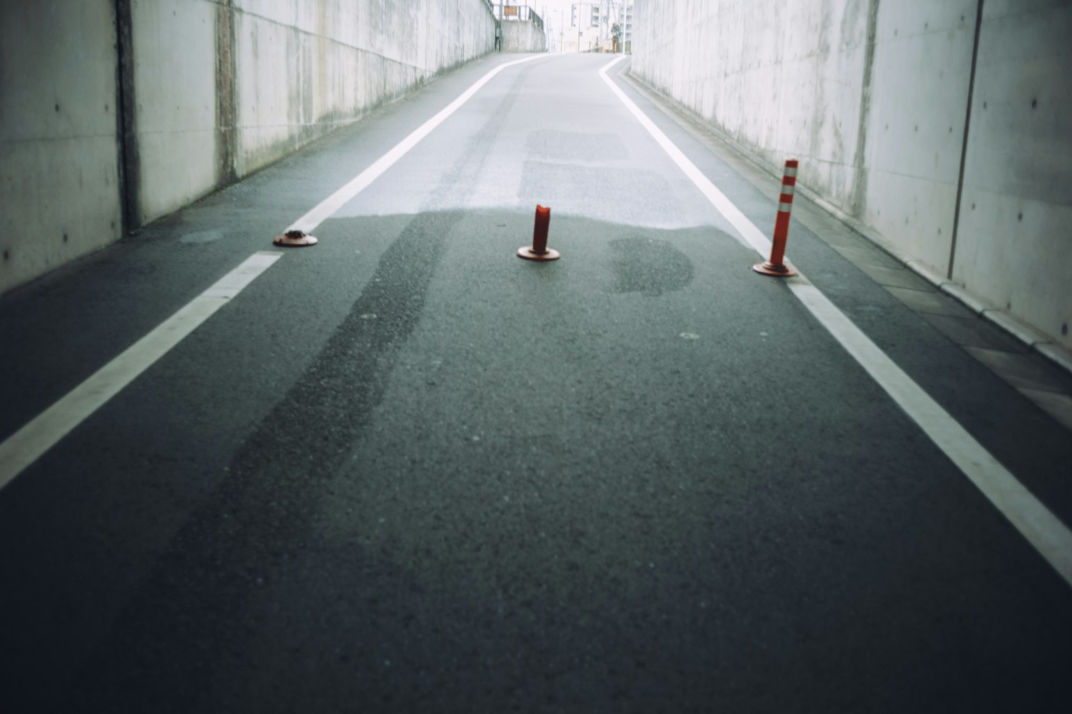 隧道内道路的照片，红色锥桶放置在沥青上