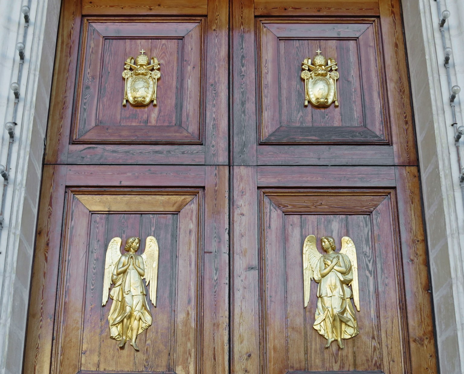 Porta in legno con sculture d'angeli dorati e stemmi