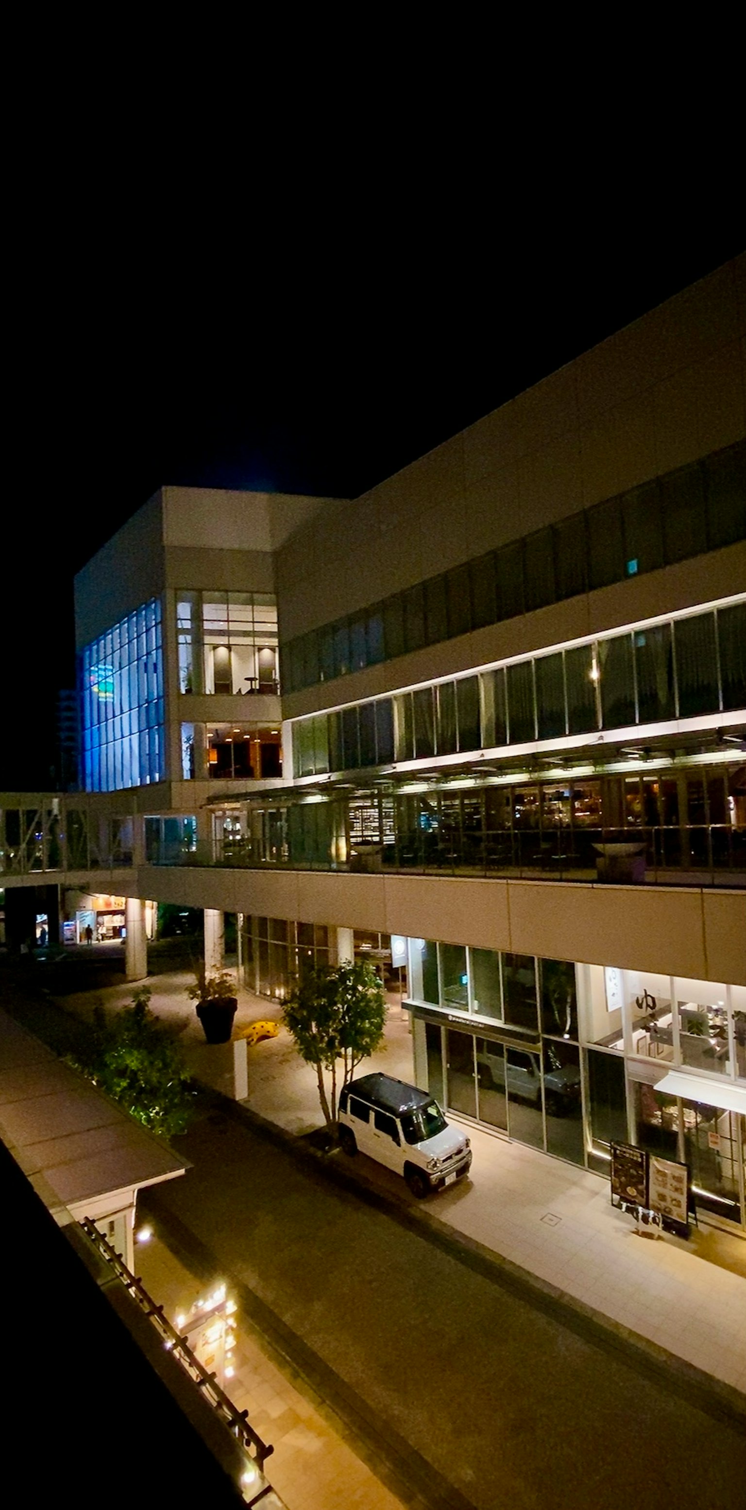 Vista esterna di un edificio commerciale di notte con terrazza illuminata