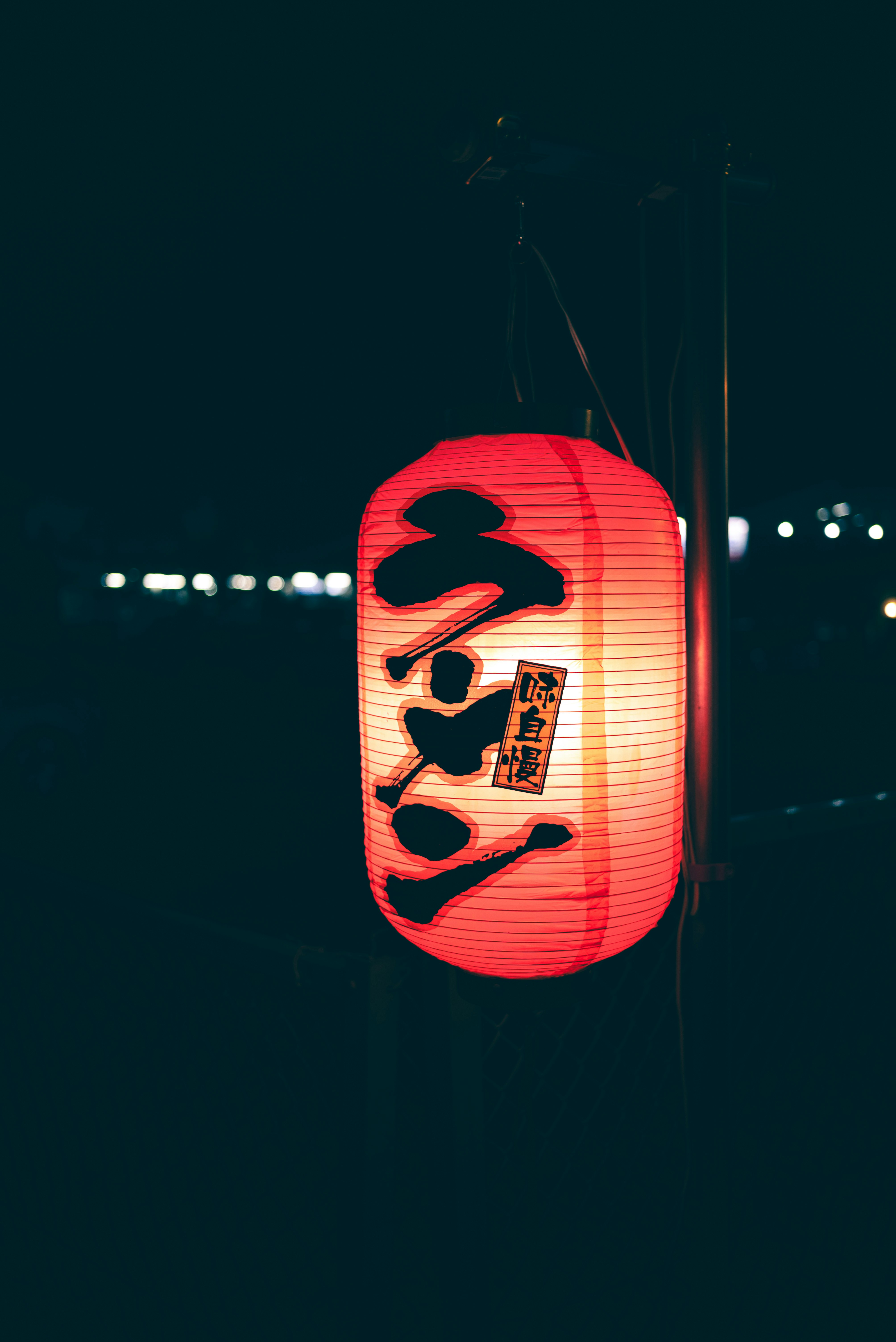 提灯のような赤いランタンの顔イラストが揺れる夜の街角