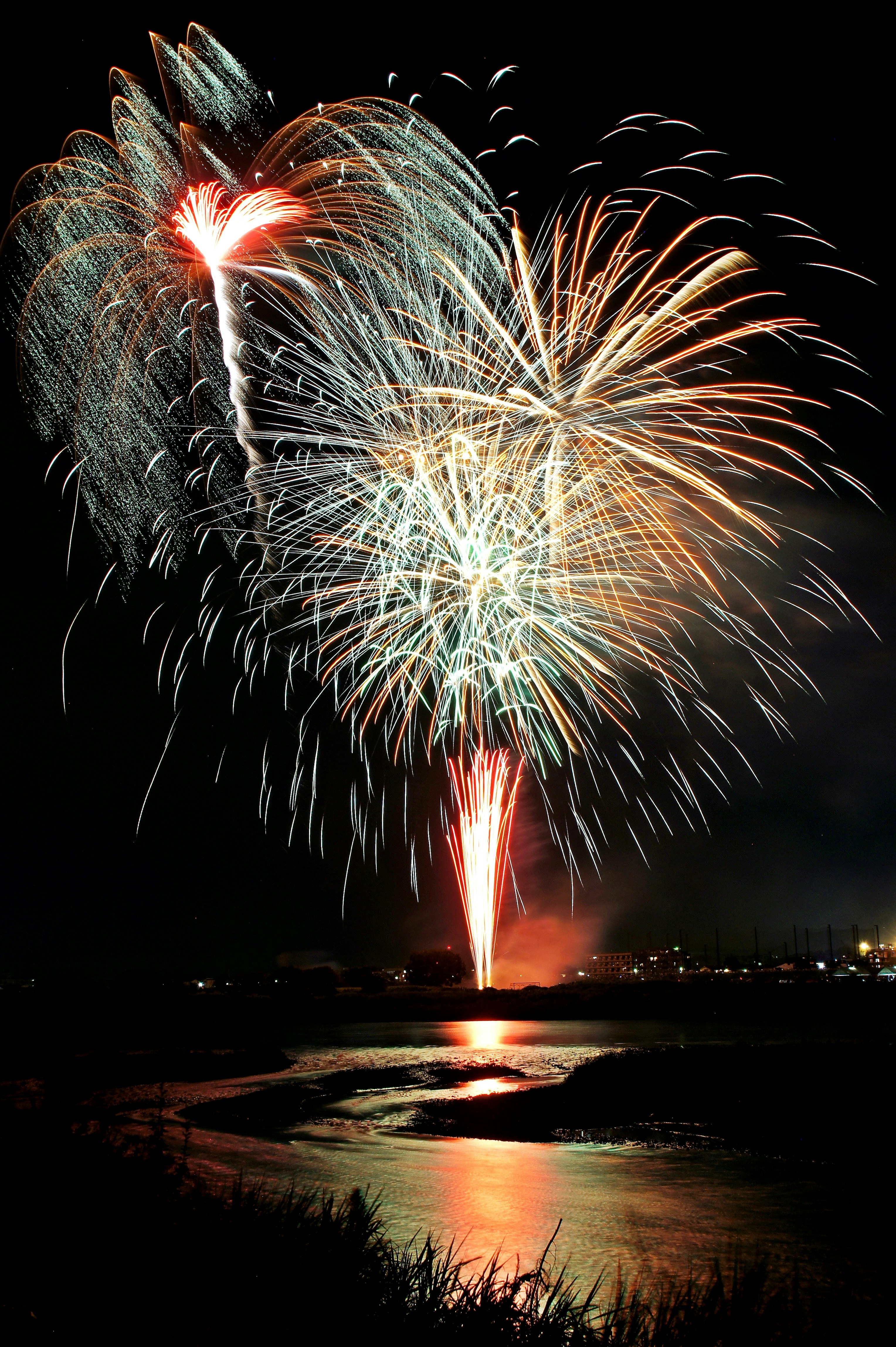 fuegos artificiales explotando sobre una superficie de agua reflectante
