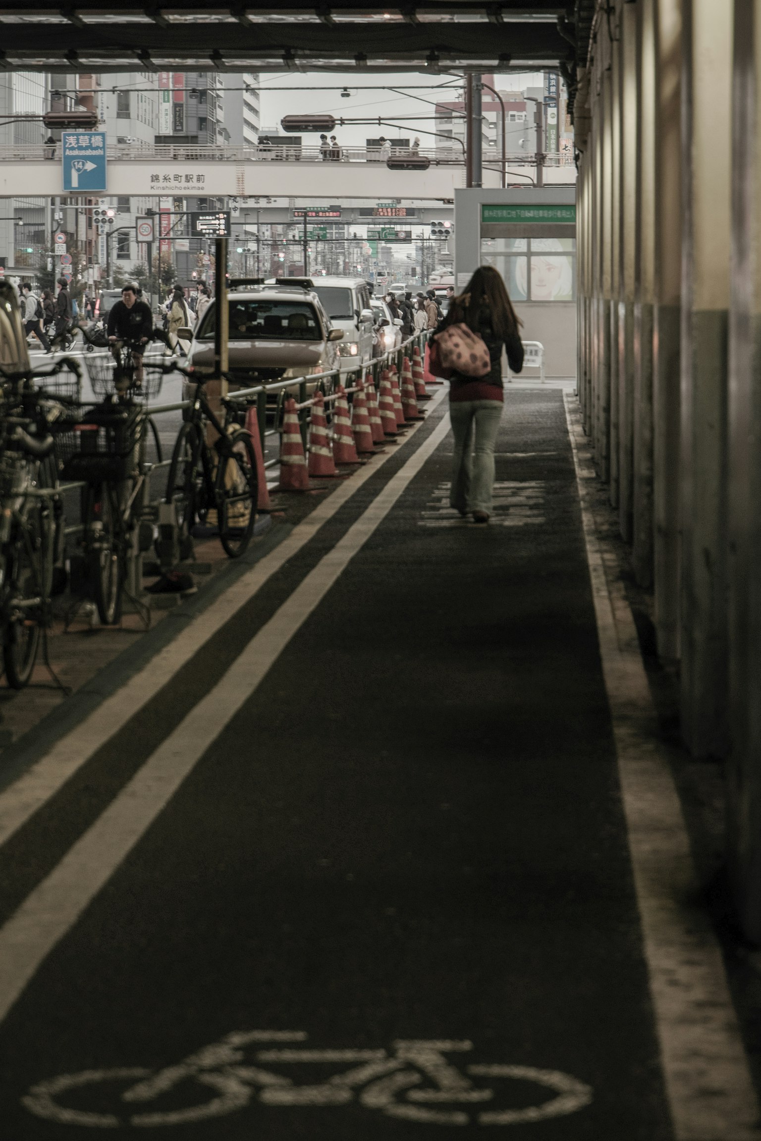 Eine Frau, die auf einem Radweg neben geparkten Fahrrädern in einer Stadtstraße geht