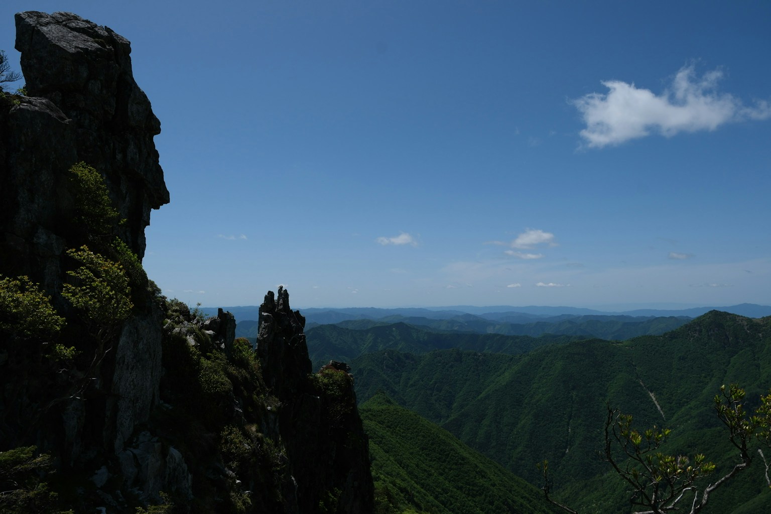 Expansive view of mountains and blue sky featuring a prominent rock outcrop