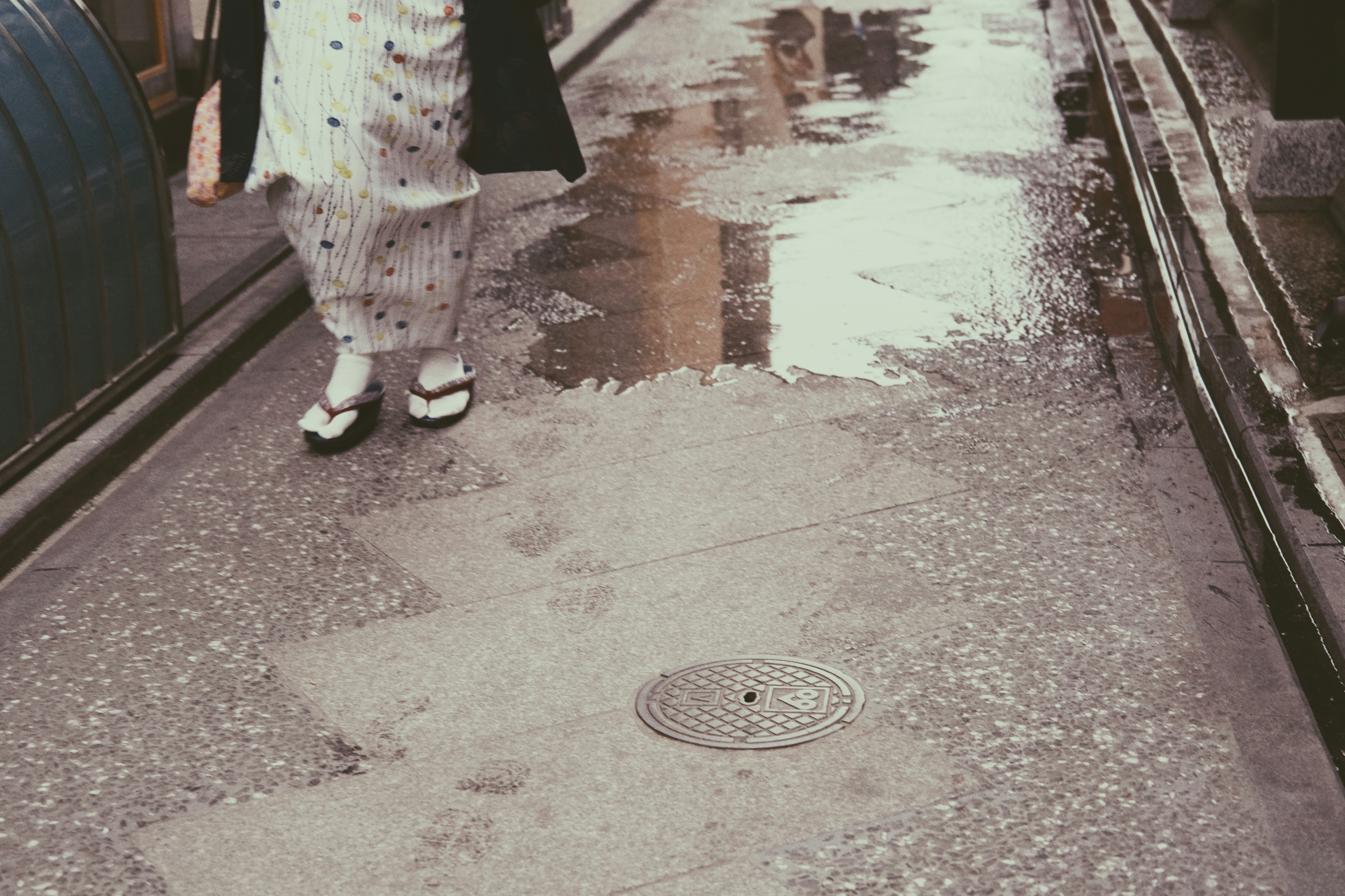 雨後巷弄濕潤石板路與兒童鞋子