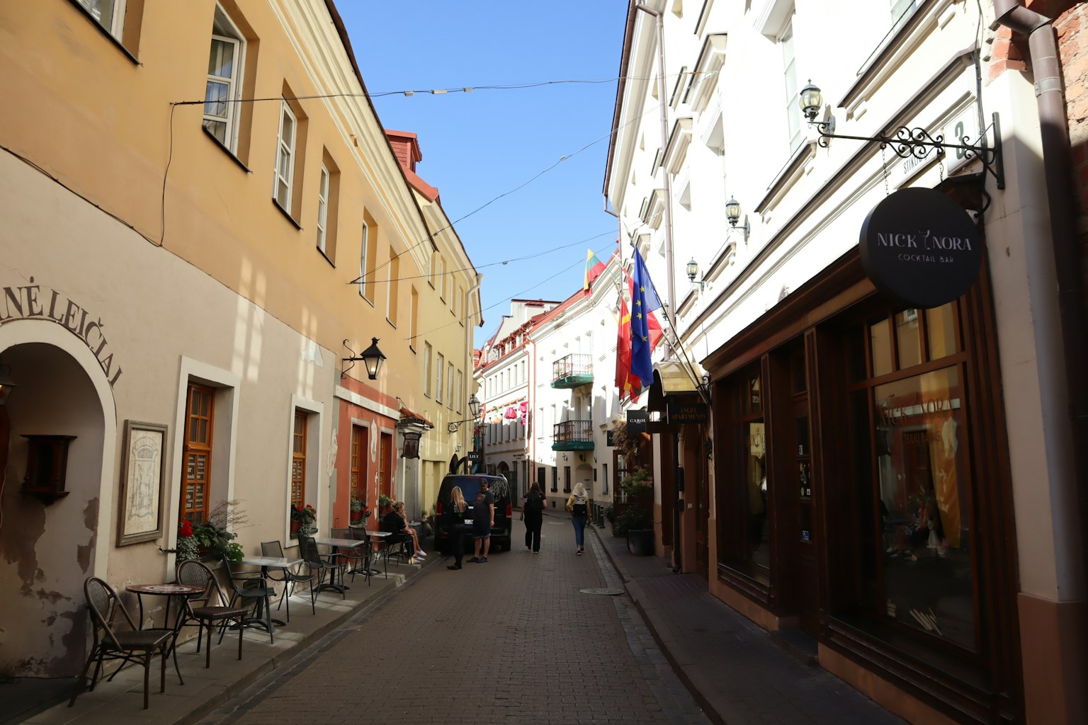 Calle estrecha flanqueada por cafés y edificios coloridos