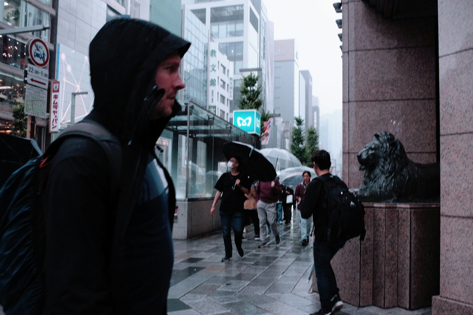一名穿着黑色连帽夹克的男子在雨中的城市环境中行走