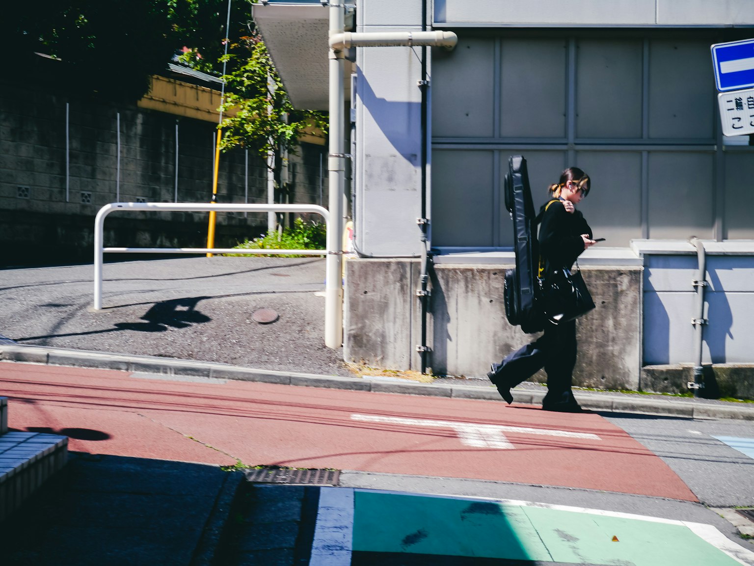 A woman walking on the street carrying a guitar case