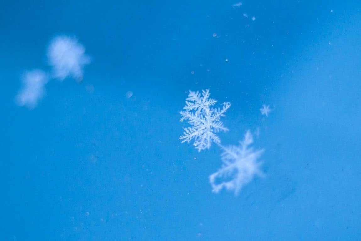 schwebende Schneeflocken vor blauem Himmel