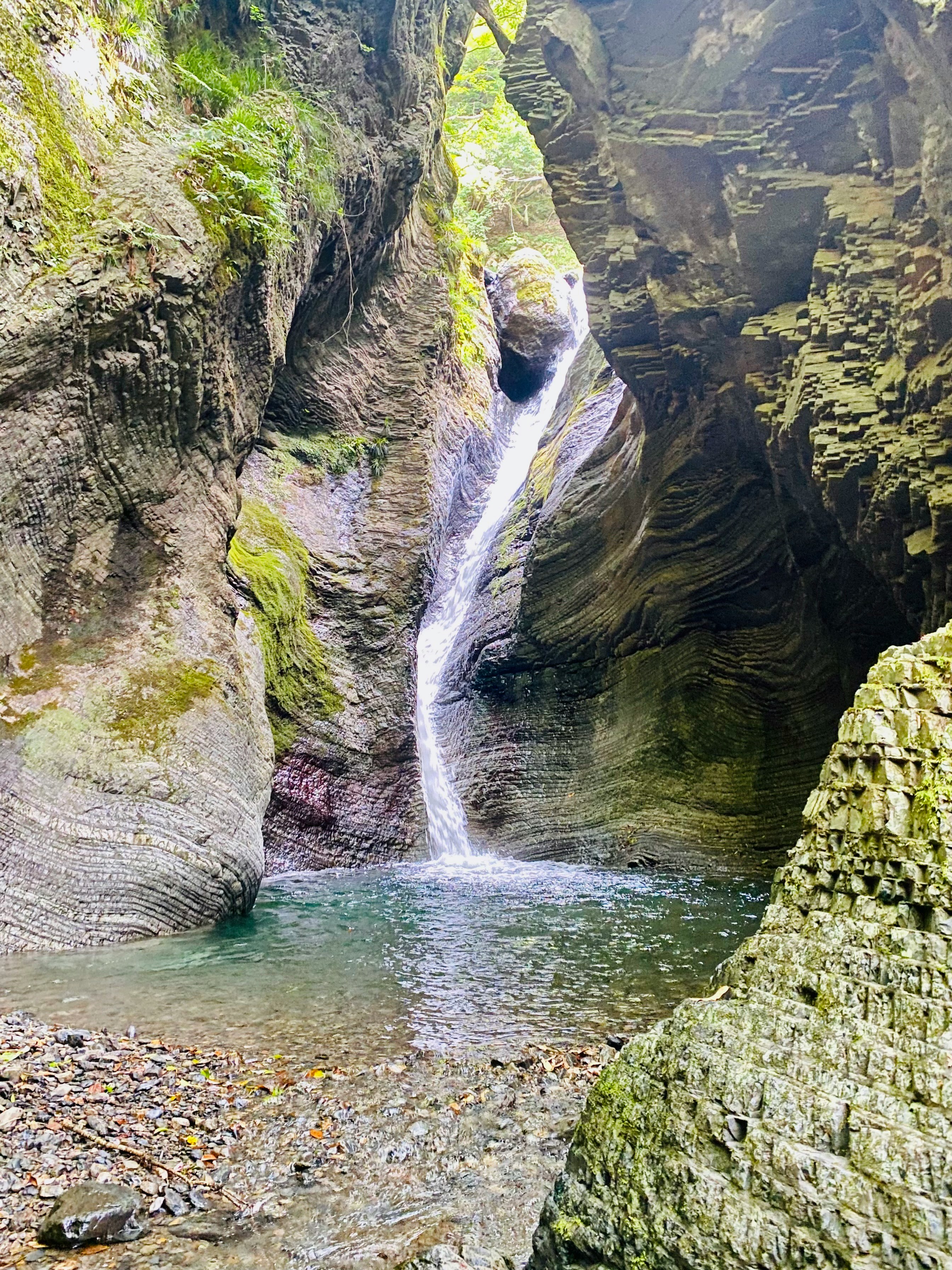 渓谷の岩壁に囲まれた滝と澄んだ水たまり